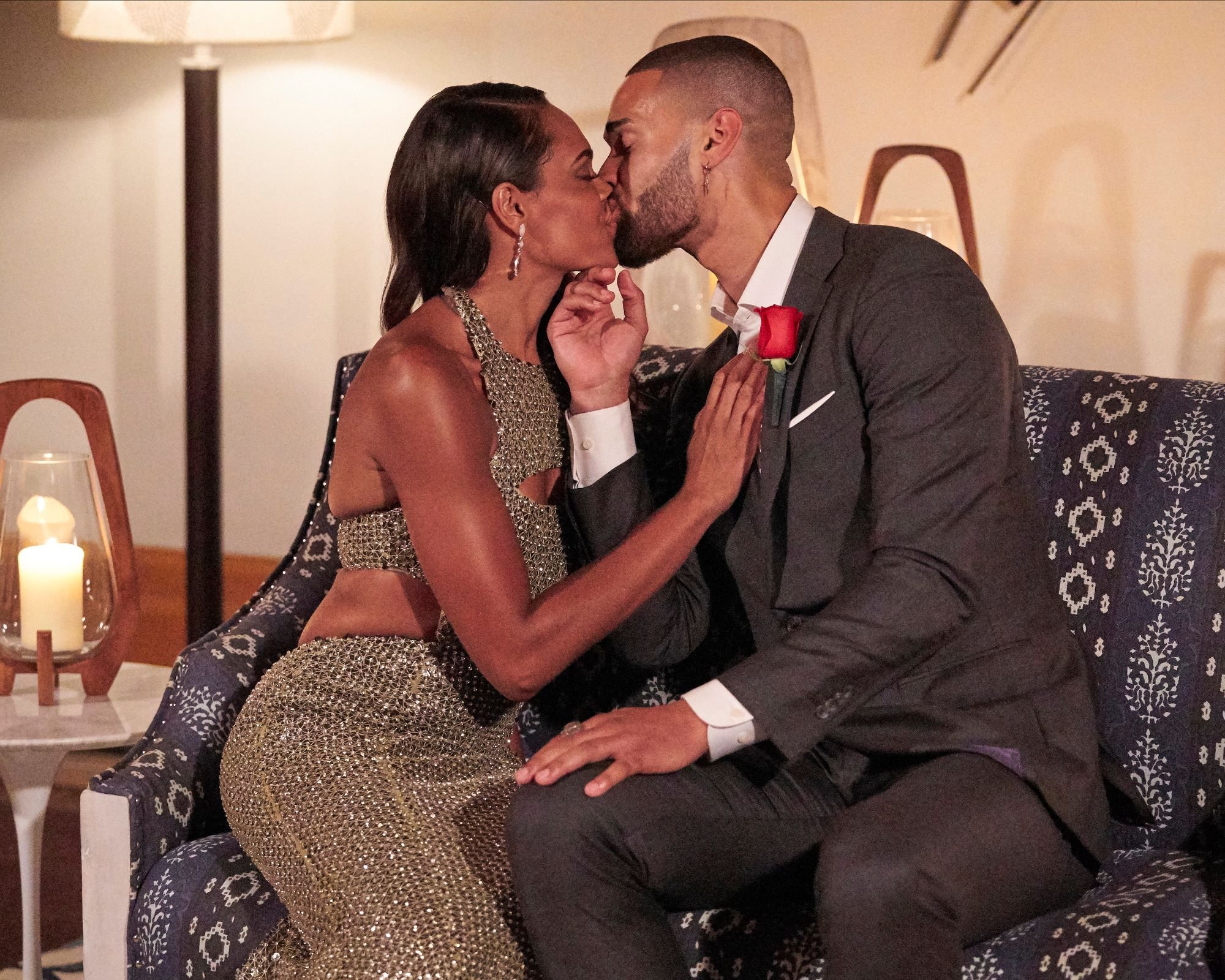 'The Bachelorette' stars Michelle Young and Nayte Olukoya share a kiss after Michelle gives Nayte her first impression rose. Michelle wears a muted green sparkly dress. Nayte wears a black suit.