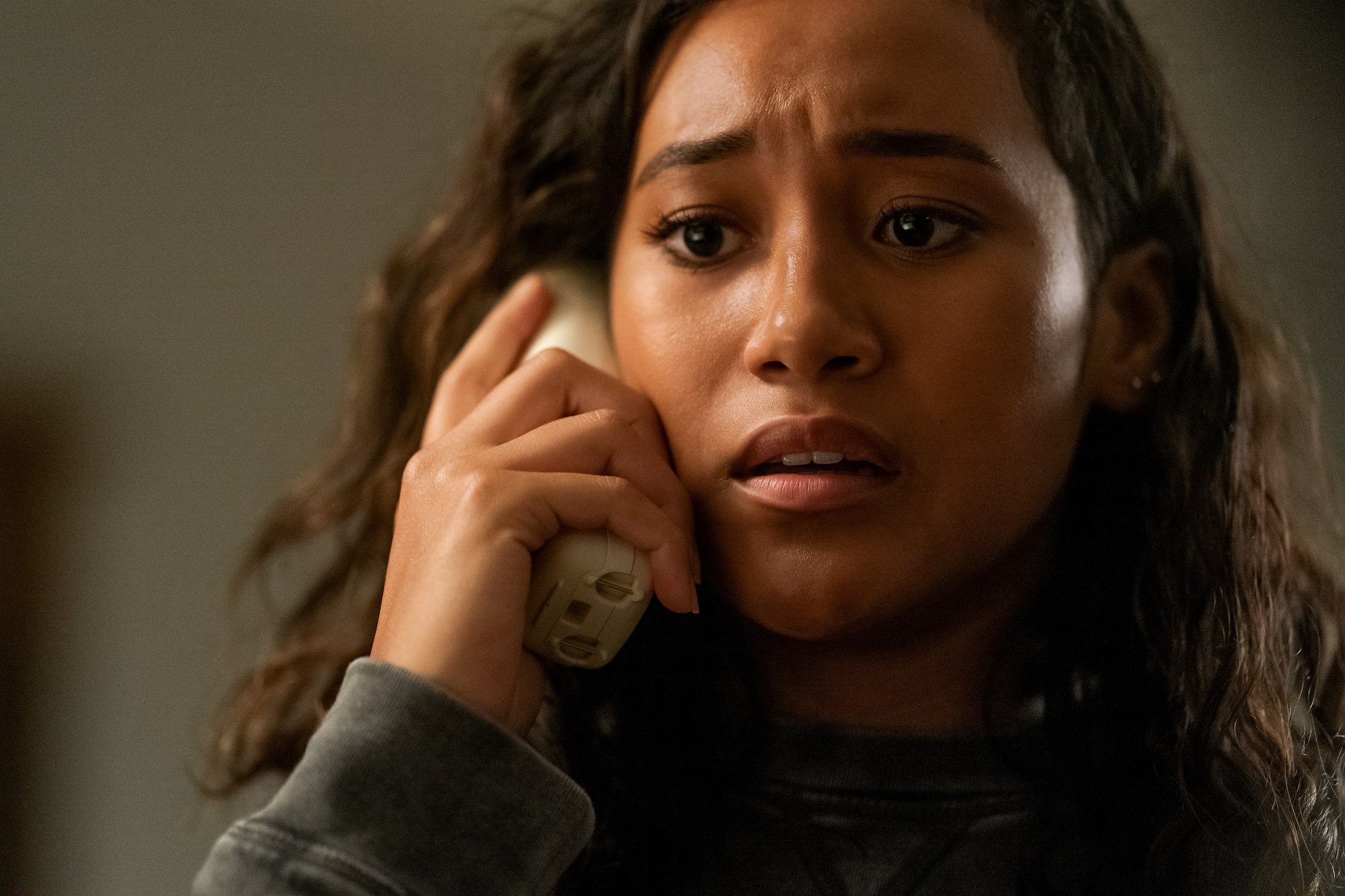 Netflix movie 'There's Someone Inside Your House' actor Sydney Park as Makani Young looking scared with a white phone