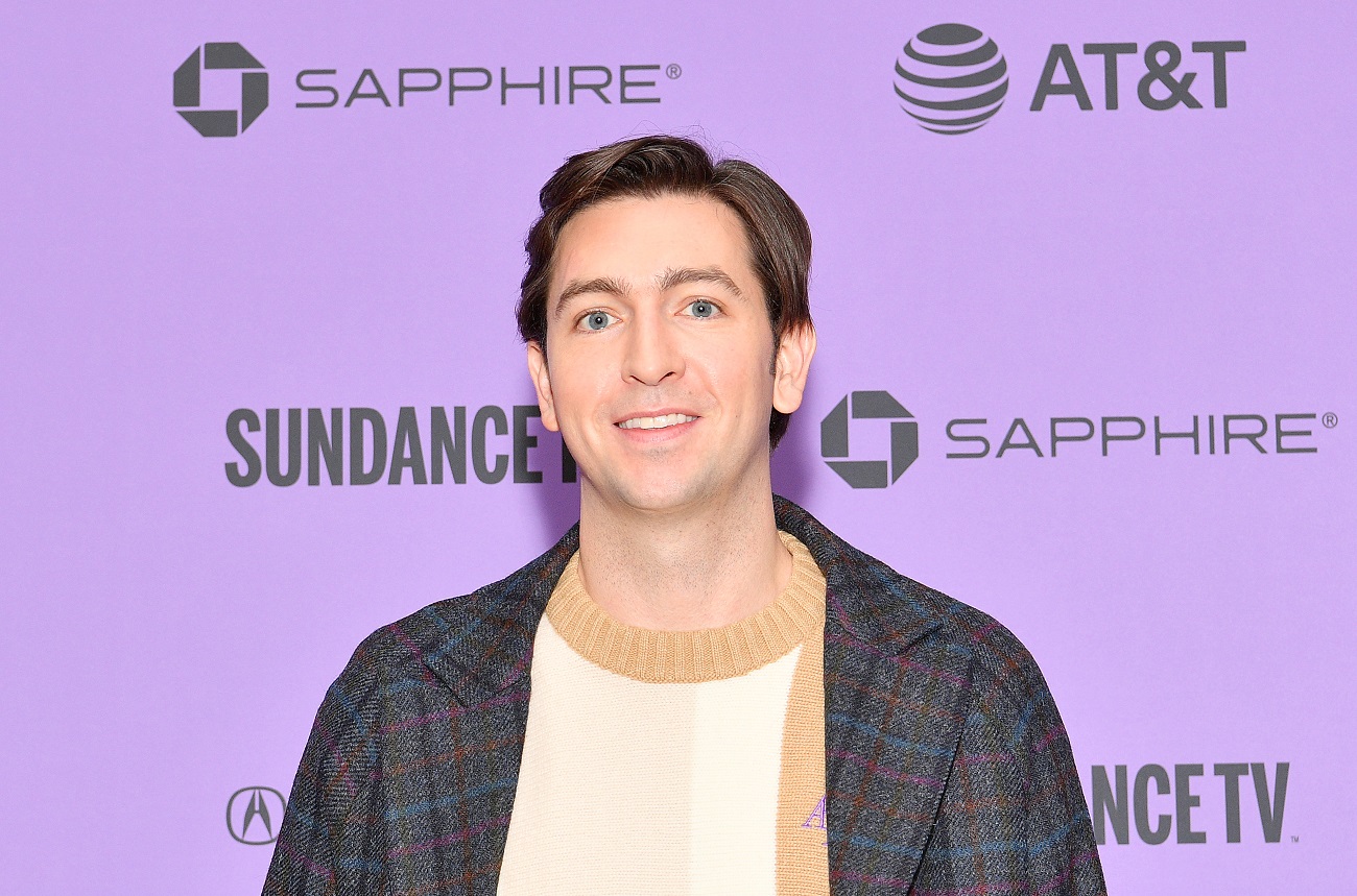 Succession actor Nicholas Braun in a tan sweater and plaid coat.
