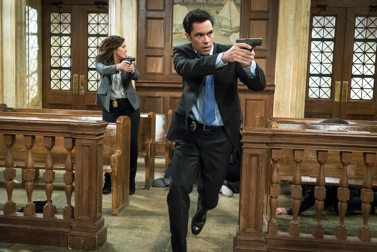 Det. Nick Amaro (Danny Pino) holding a gun and running in a courtroom in 'Law & Order: SVU'