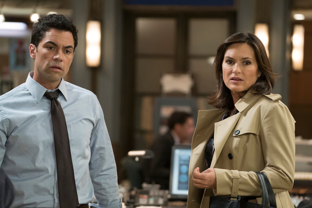 Det. Nick Amaro (Danny Pino) in shirt and tie standing next to Olivia Benson (Mariska Hargitay) in a trench coat in 'Law & Order: SVU'