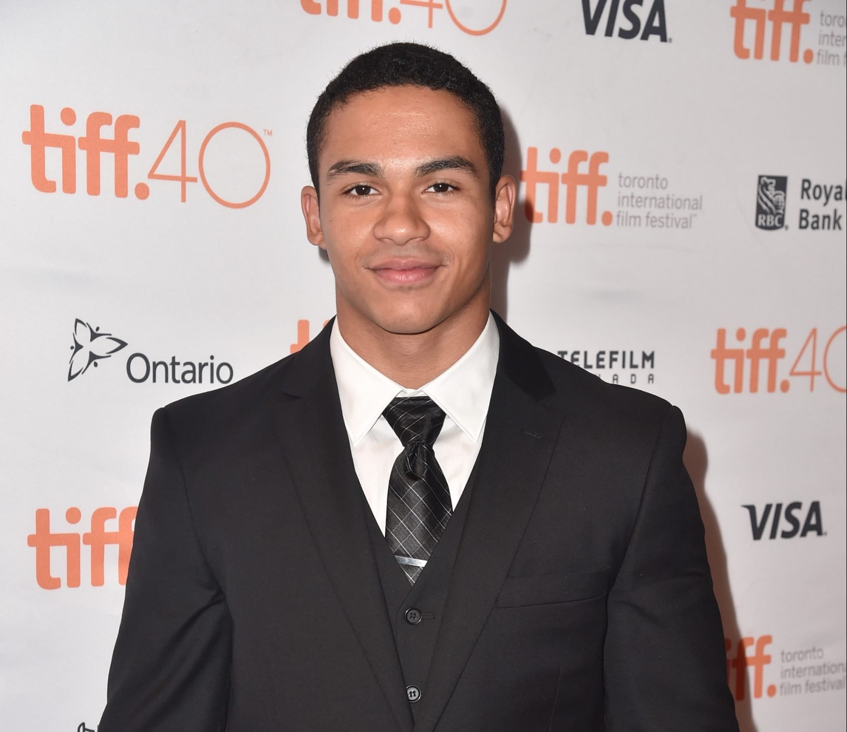 Noah Gray-Cabey wearing an all black suit to 2015 'Heroes Reborn' premiere
