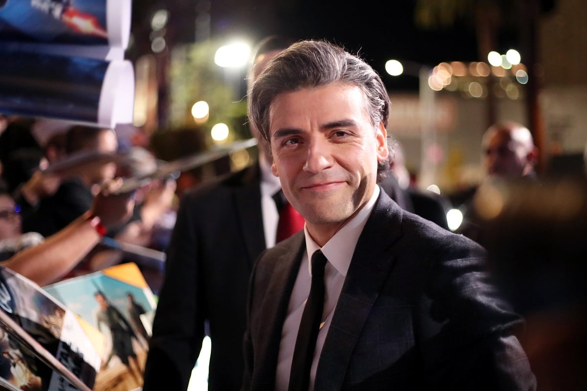 Oscar Isaac smirking in a suit