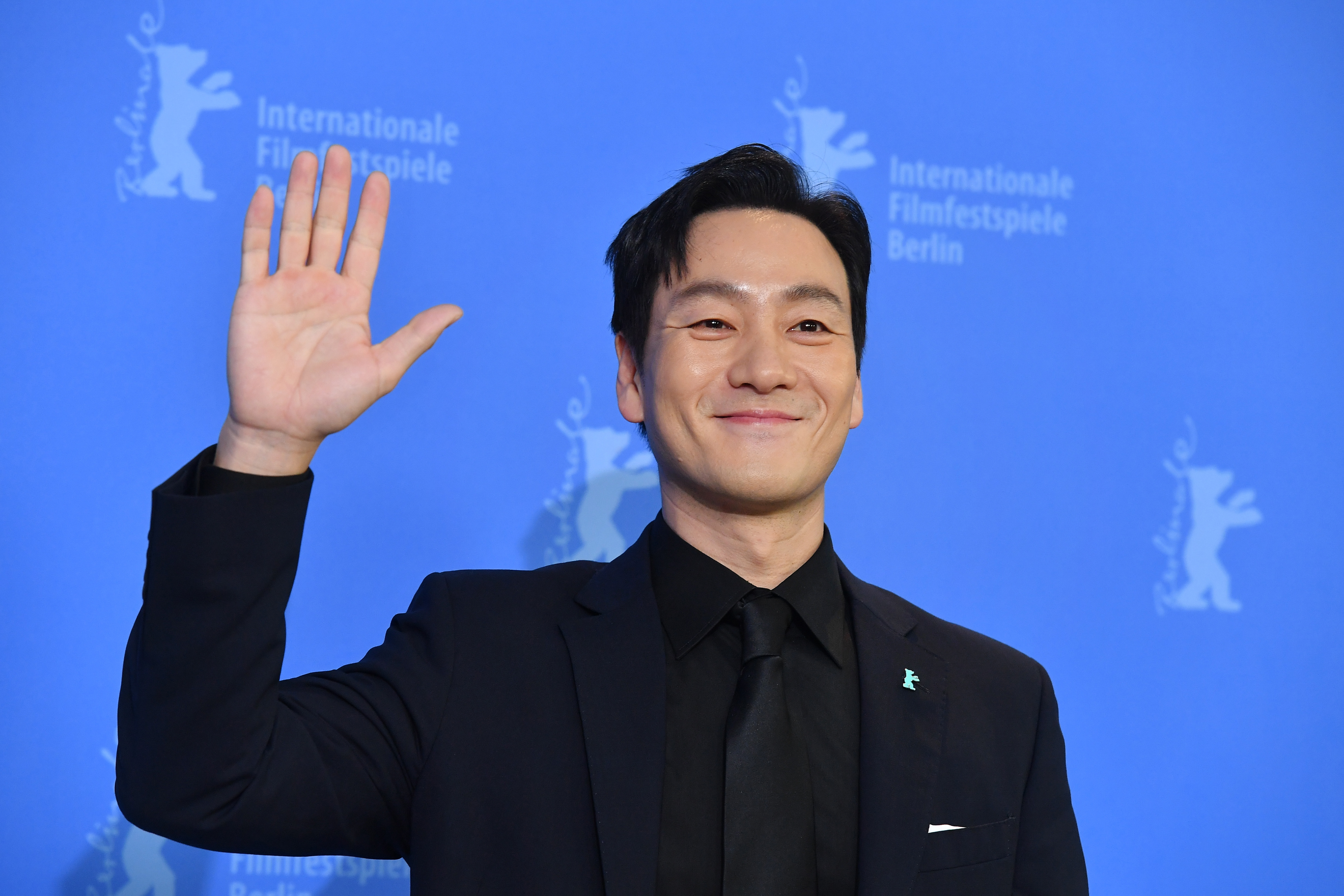 Park Hae-soo as Berlin in 'Money Heist' K-drama remake wearing black suit in front of blue background