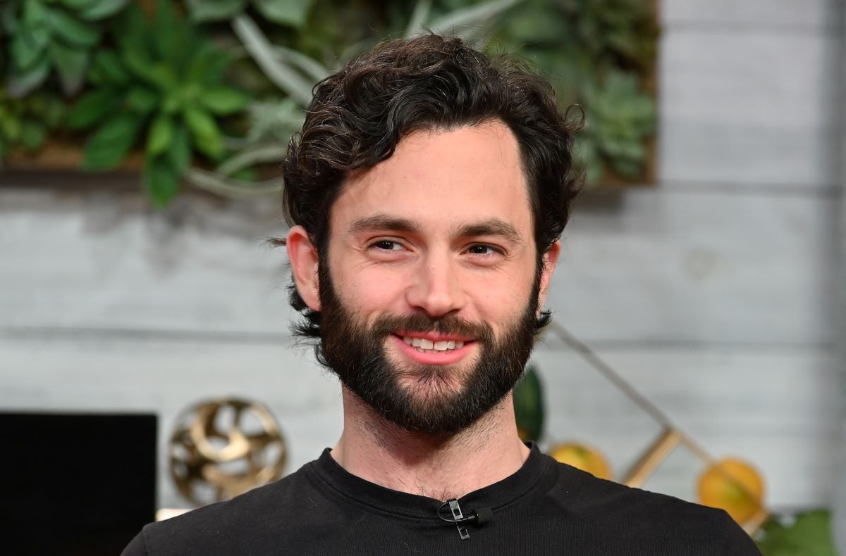 Penn Badgley with a beard, smiling