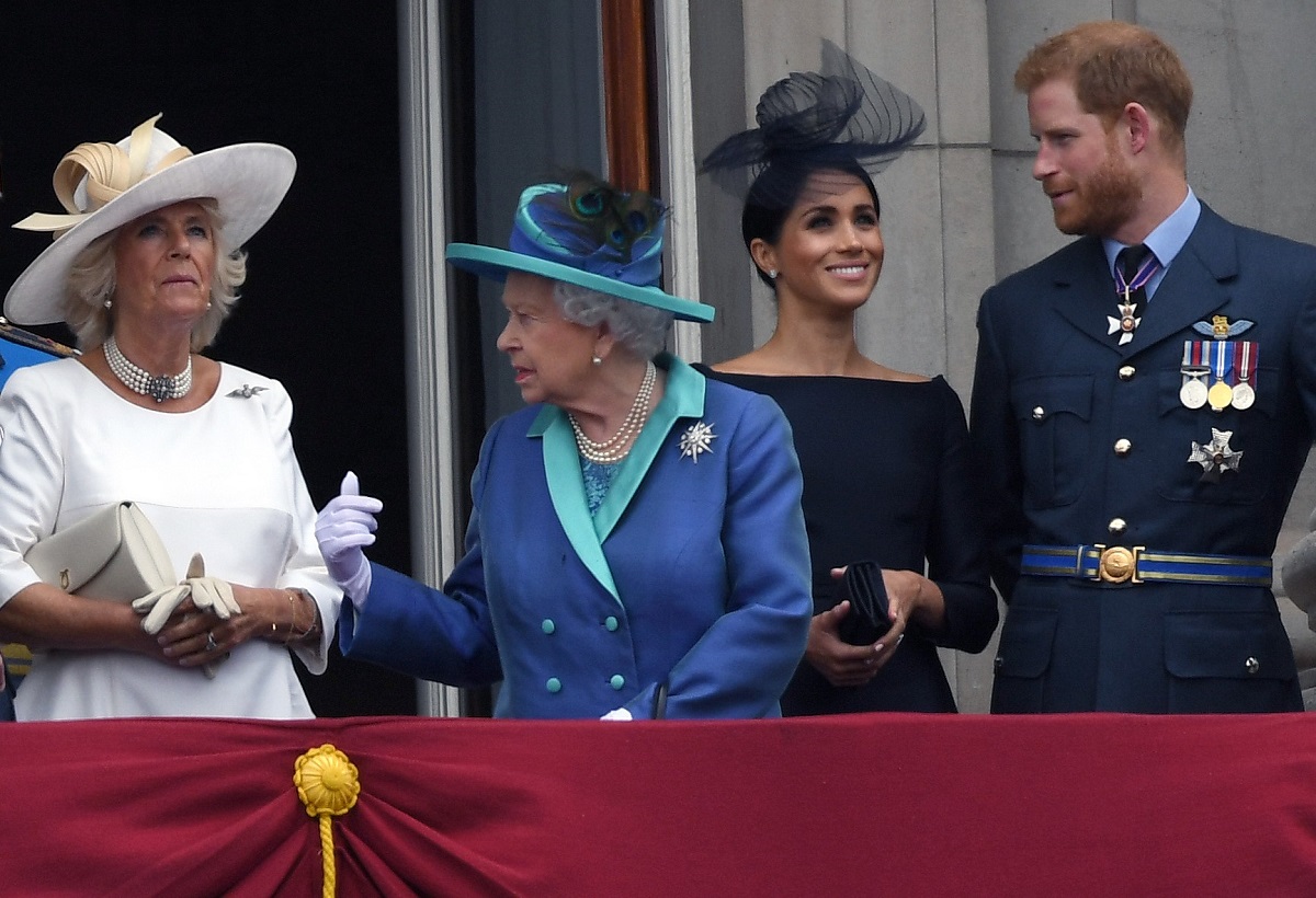 Prince Harry, Camilla Parker Bowles, and Meghan Markle stand on the balcony of Buckingham Palace to view a flypast