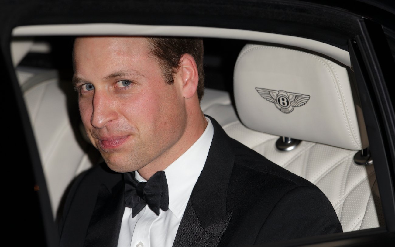 Prince William smirks wearing a tuxedo and sitting in the backseat of a car