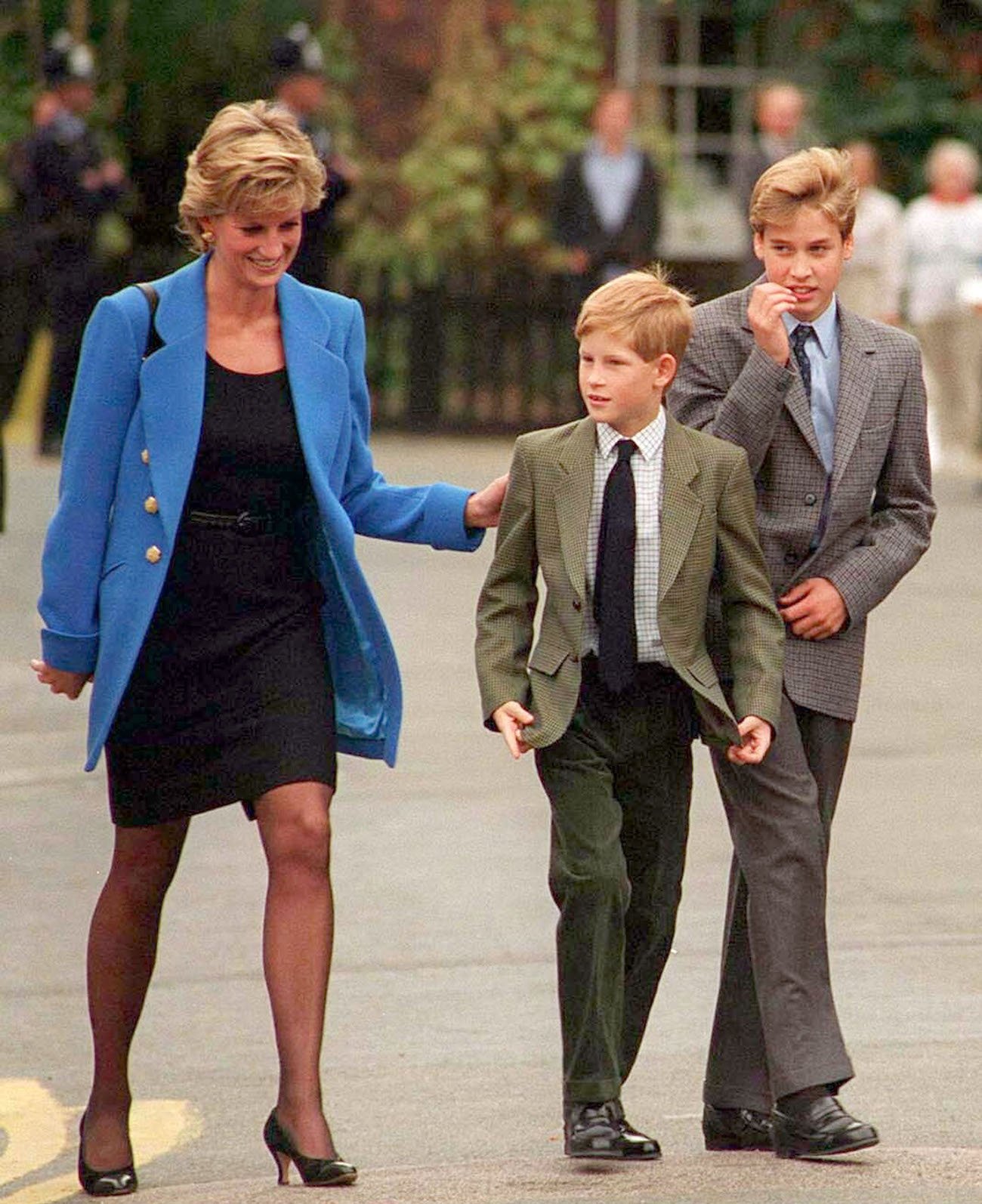 Princess Diana puts her arm on Prince Harry's shoulder as Prince William walks along