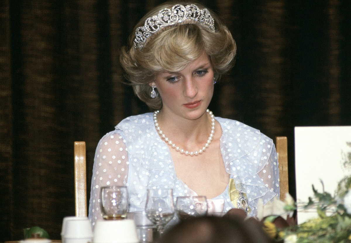Princess Diana at a banquet wearing a blue chiffon dress, pearls, drop earrings, and a tiara