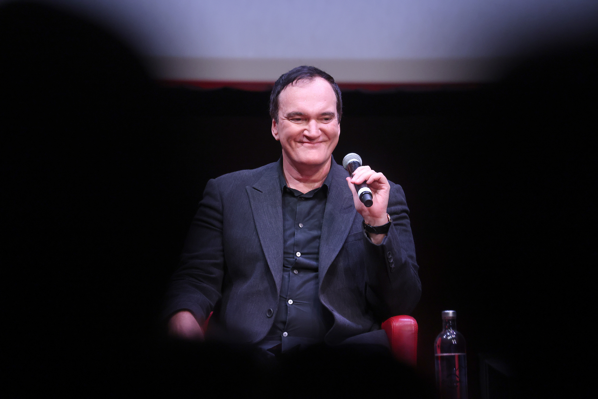 Quentin Tarantino at the Rome Film Festival smiling with a mic in hand