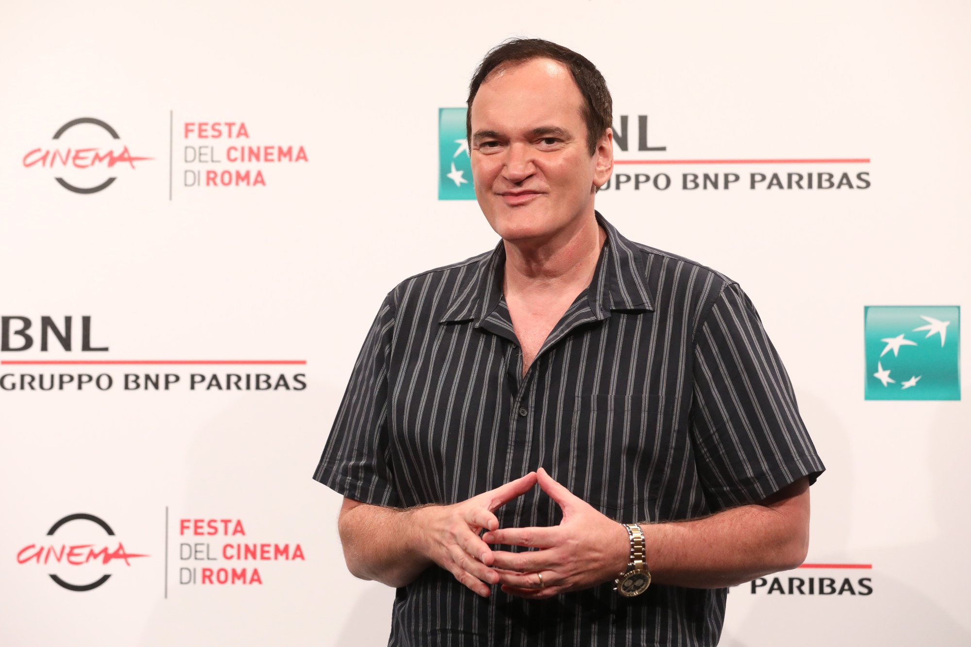 Quentin Tarantino at the Rome Film Festival photocall touching his fingertips wearing a pinstriped shirt