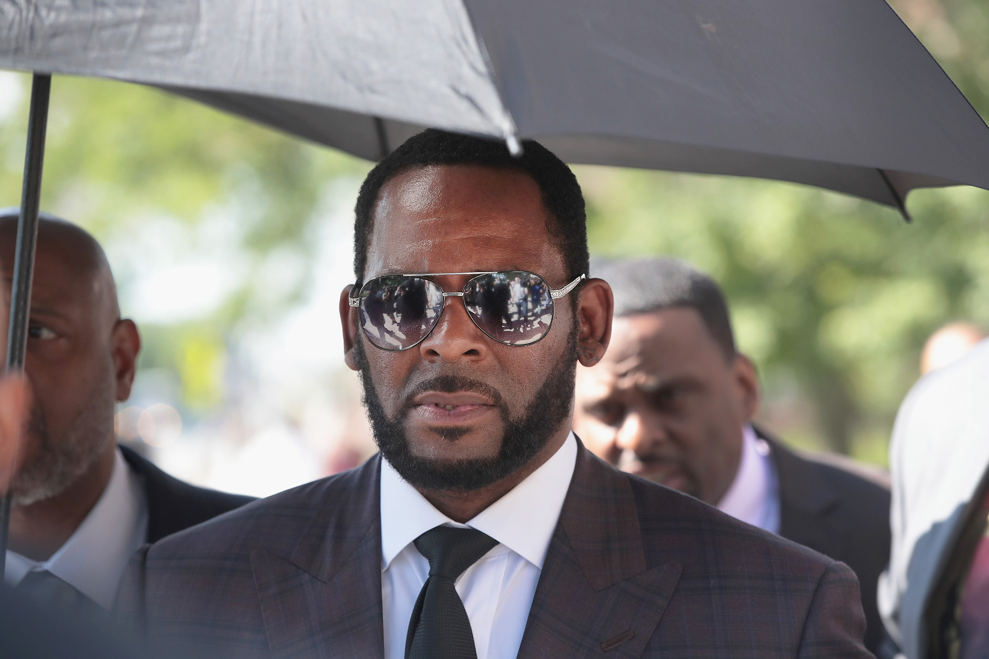 R. Kelly stands under an umbrella outside the courthouse
