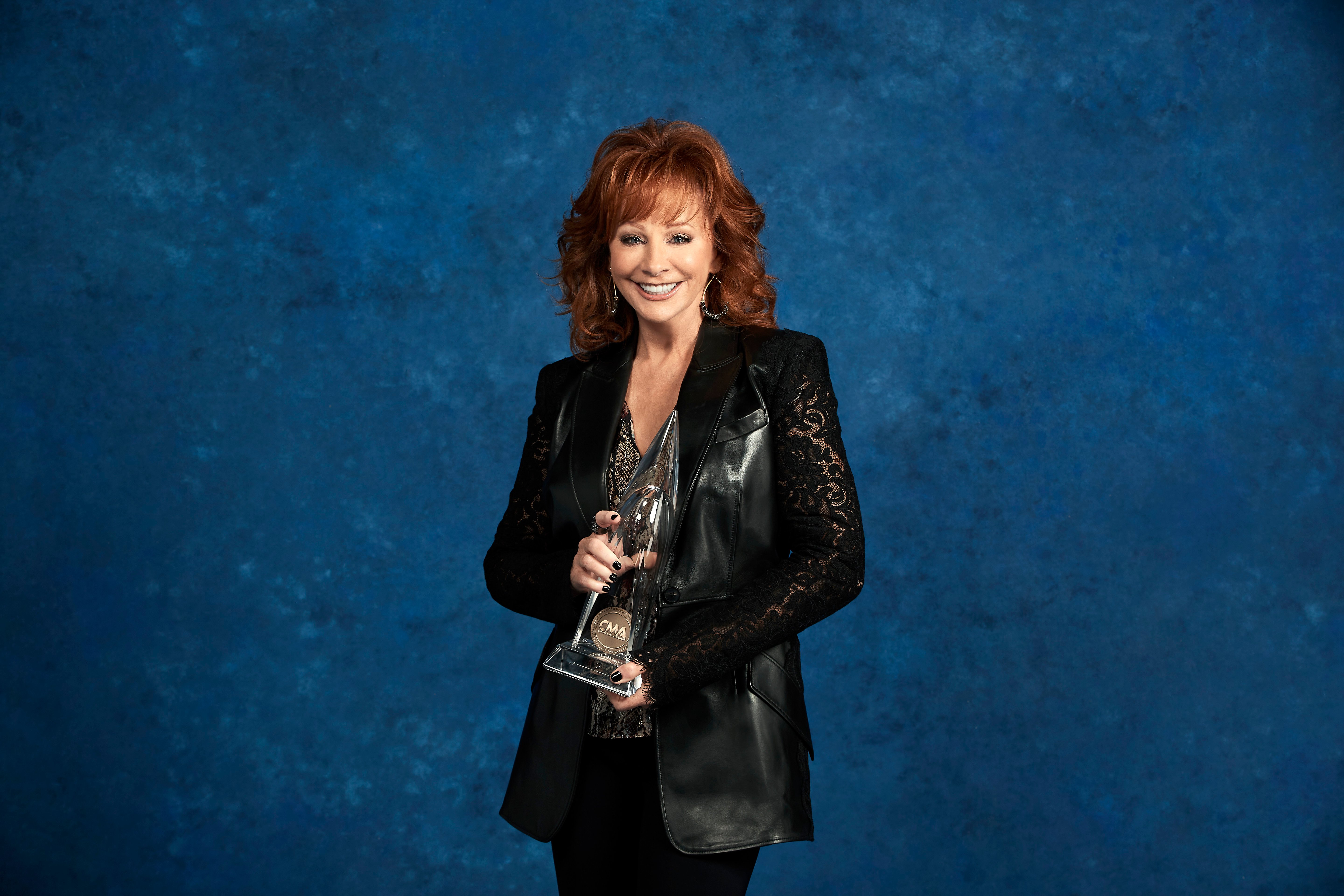 Reba McEntire posing holding a CMA Award