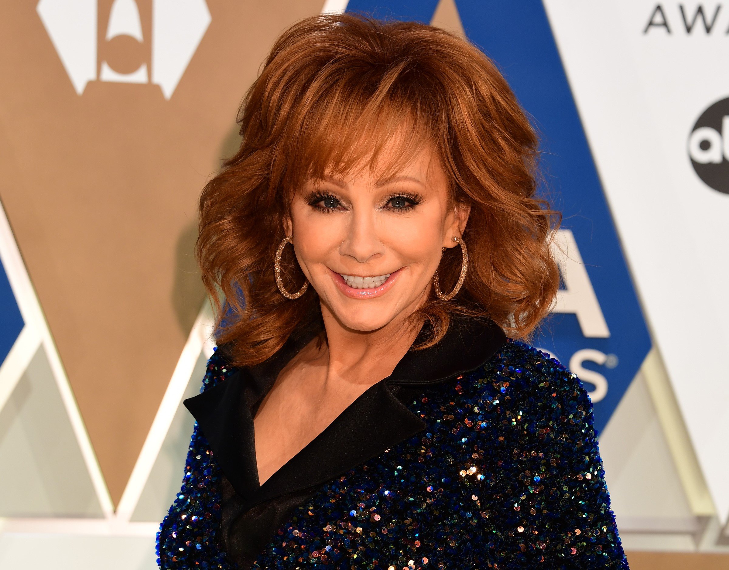 Reba McEntire smiling on the red carpet in a sequins gown at the 54th Annual CMA Awards