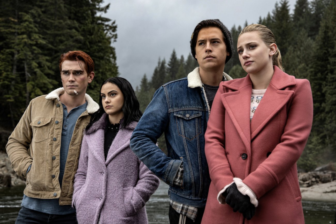 KJ Apa, Camila Mendes, Cole Sprouse, and Lili Reinhart in 'Riverdale' Season 5, which airs its finale in October. They're all wearing winter coats and the sky behind them is grey.