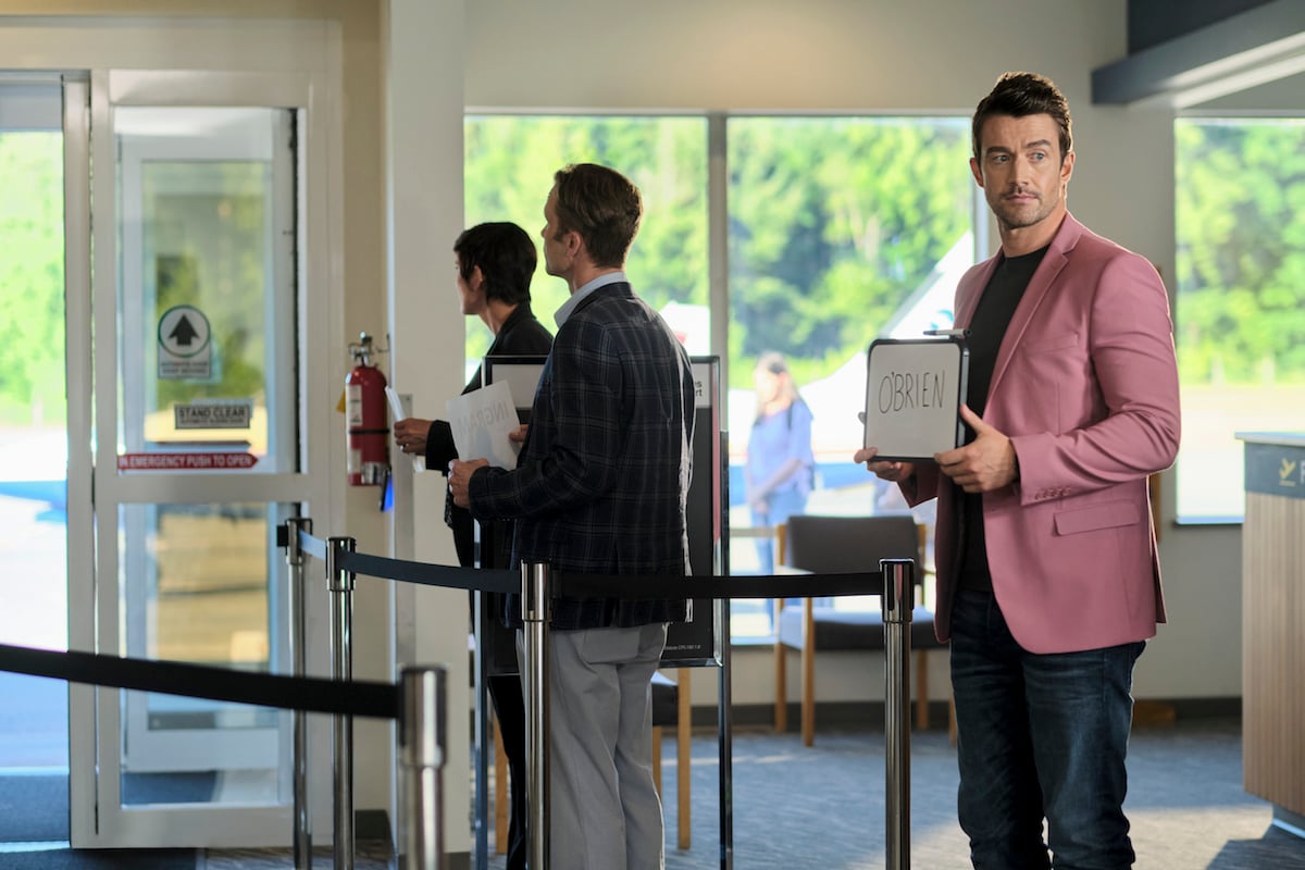 Evan (Robert Buckley) holding a sign as he waits for Abby at the airport in the 'Chesapeake Shores' Season 5 finale