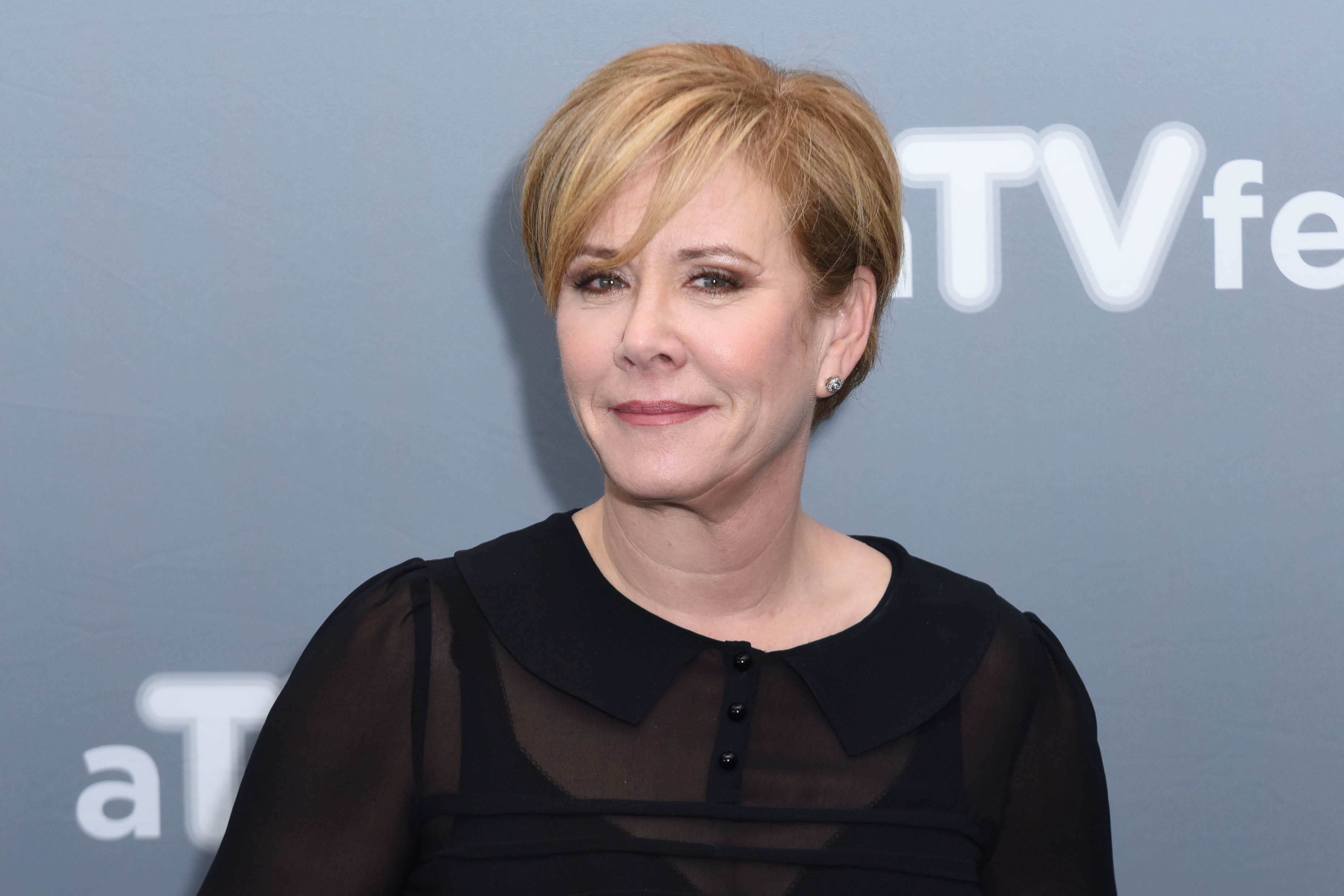 Romy Rosemont smiles for a photo. She has short blonde hair and is wearing a black top.