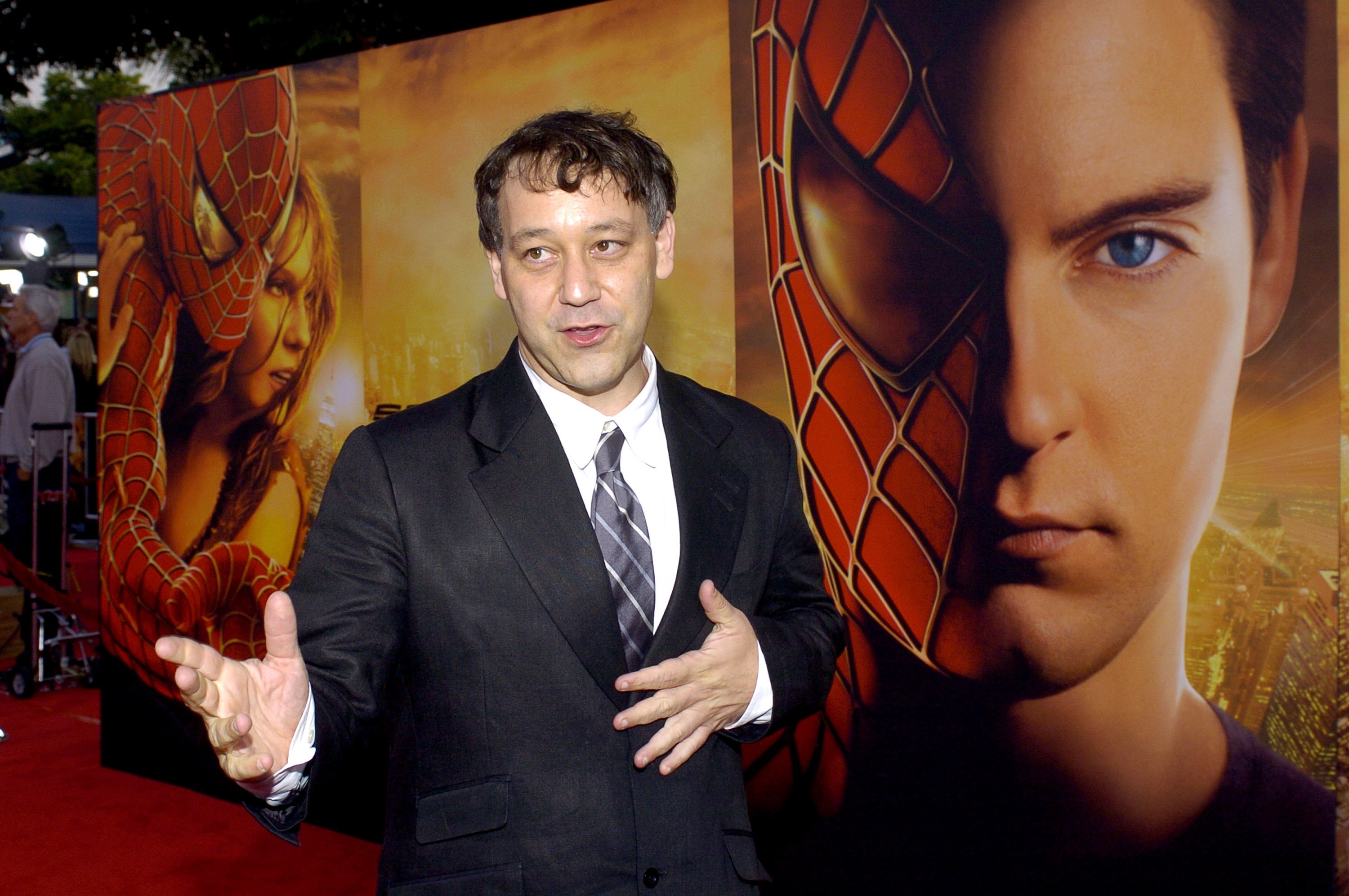 'Doctor Strange in the Multiverse of Madness' director Sam Raimi wears a black suit coat, white button-up shirt, and gray and white striped tie.