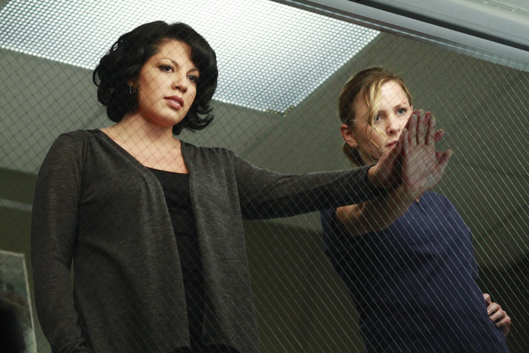 Sara Ramirez, and Jessica Capshaw holding hands in a hospital room in 'Grey's Anatomy.'