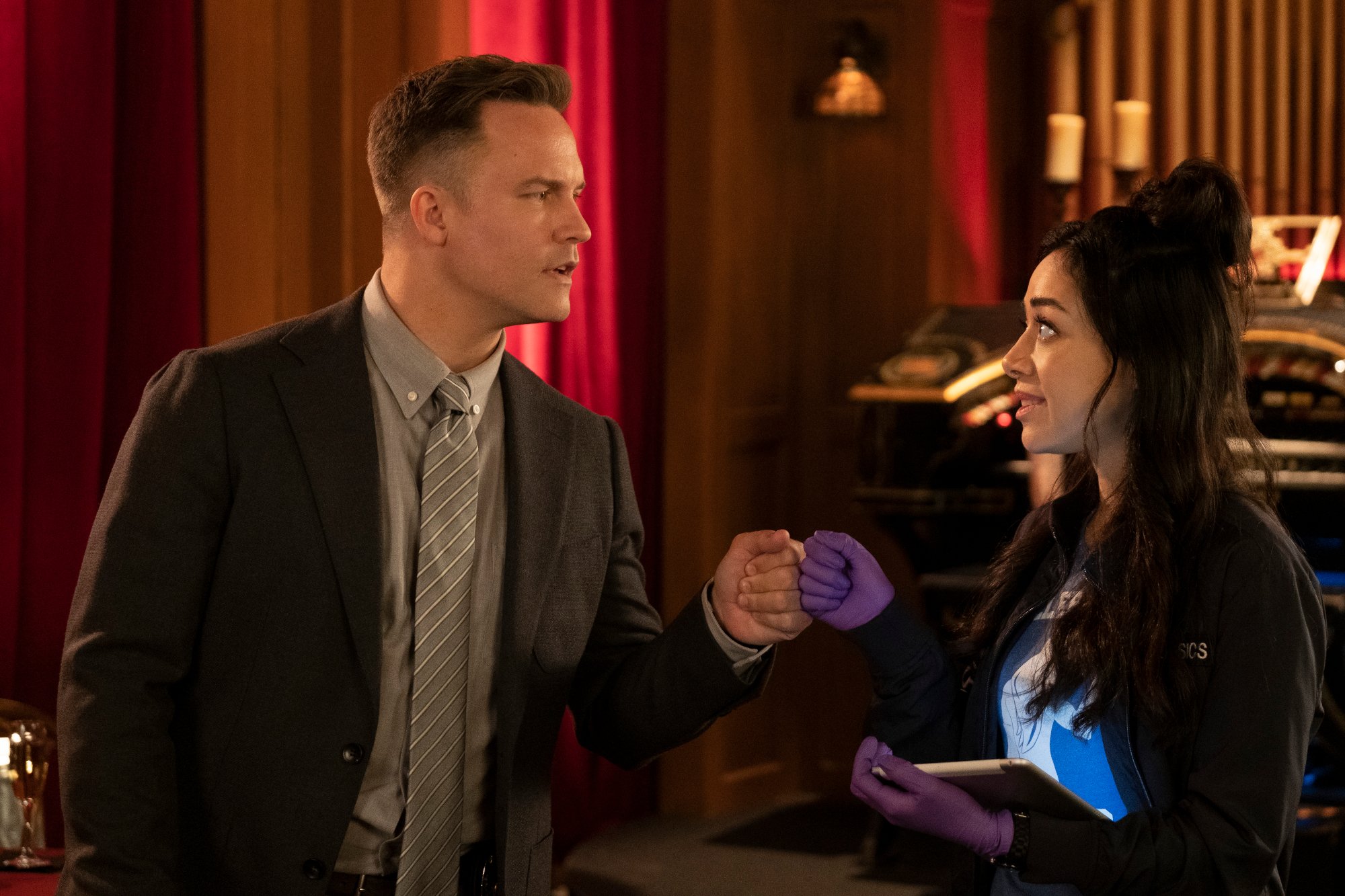Scott Porter and Aimee Garcia as Carol and Ella in 'Lucifer' Season 6 on Netflix. They're awkwardly fist-bumping one another.