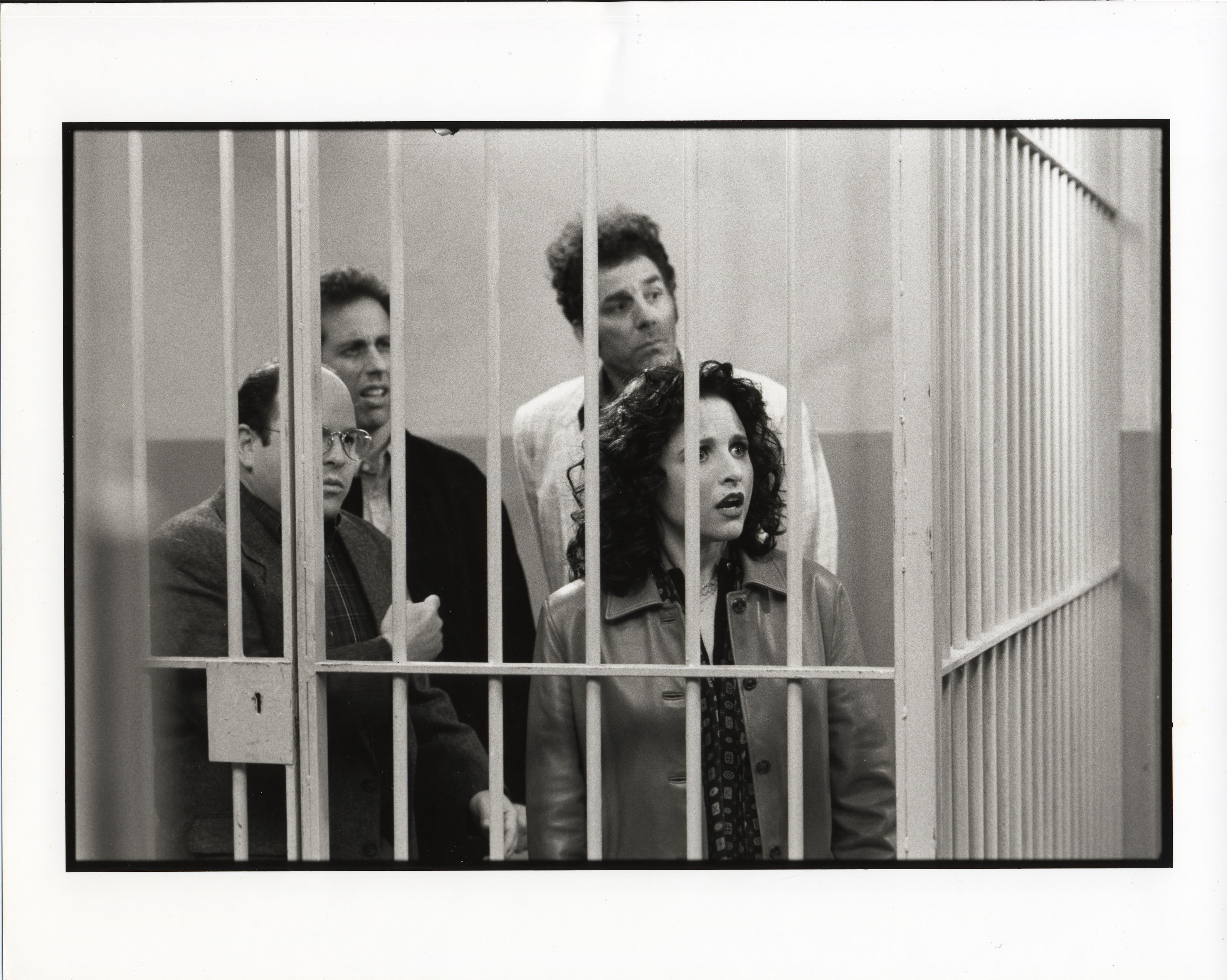 Jason Alexander (George), Jerry Seinfeld (Jerry), Michael Richards (Kramer), and Julia Louis-Dreyfus (Elaine) stand behind bars in a scene during the last days of filming the final episode of 'Seinfeld'