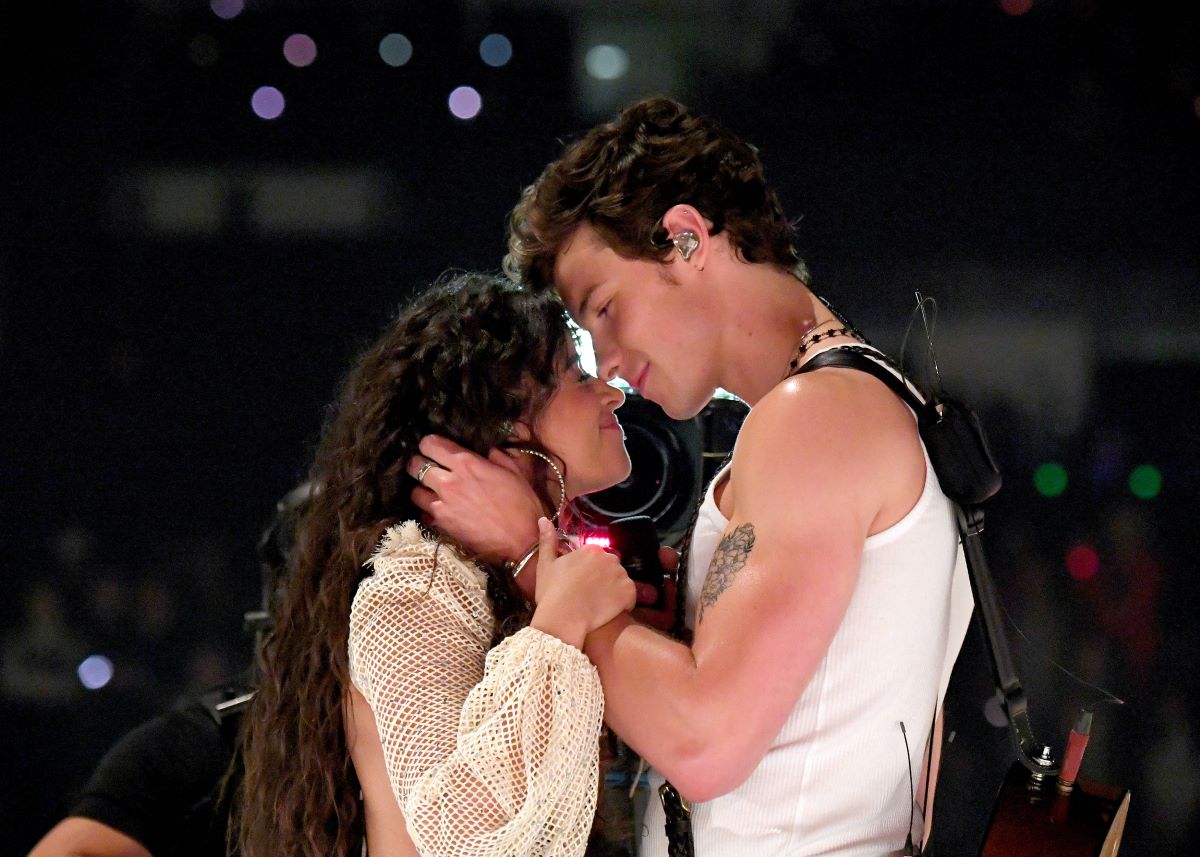 Camila Cabello closes her eyes as Shawn Mendes holds her head and looks down at her