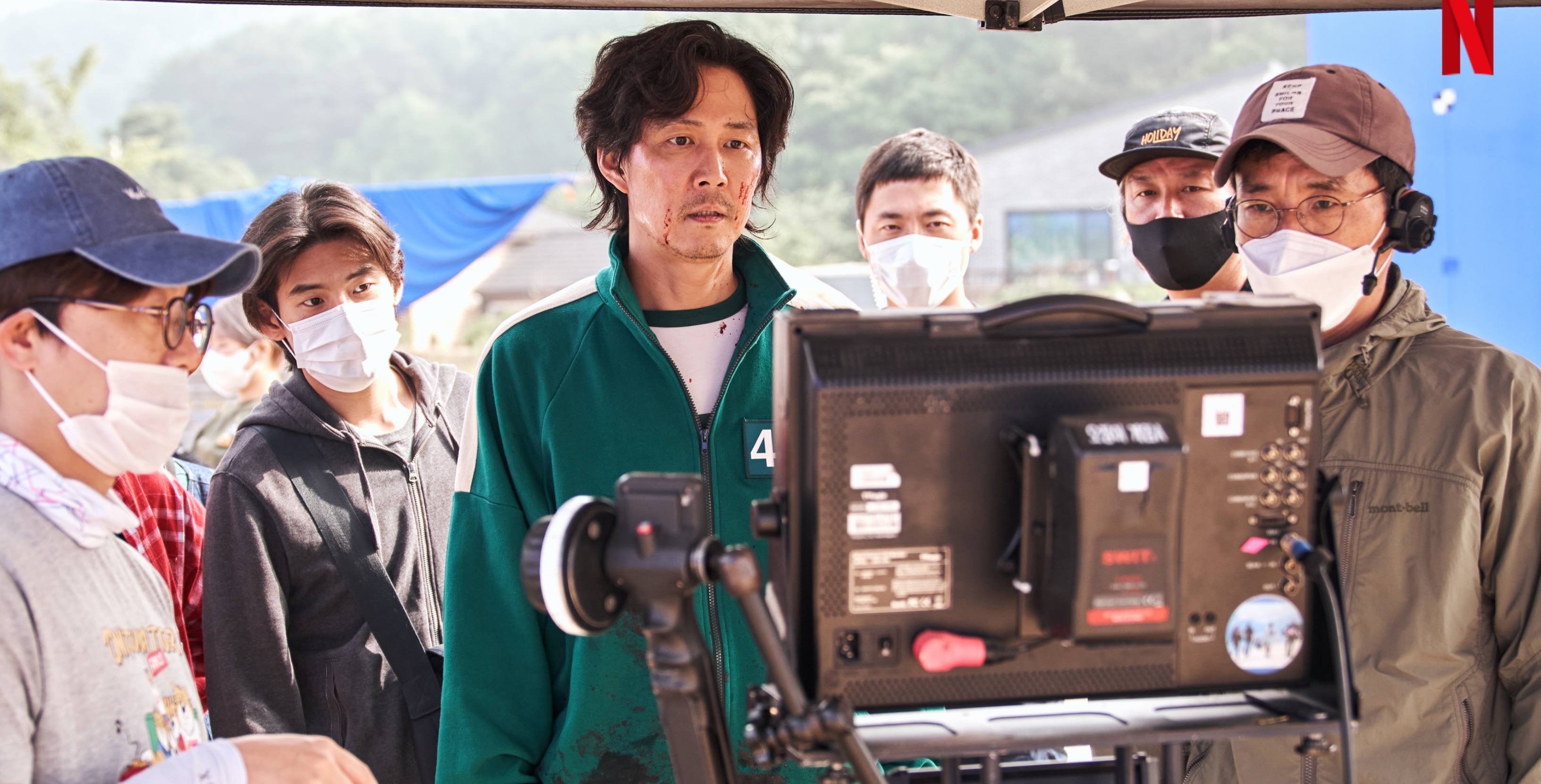 South Korean actor Lee Jung-jae and Hwang Dong-Hyuk for 'Squid Game' wearing tracksuit and staring camera monitor.
