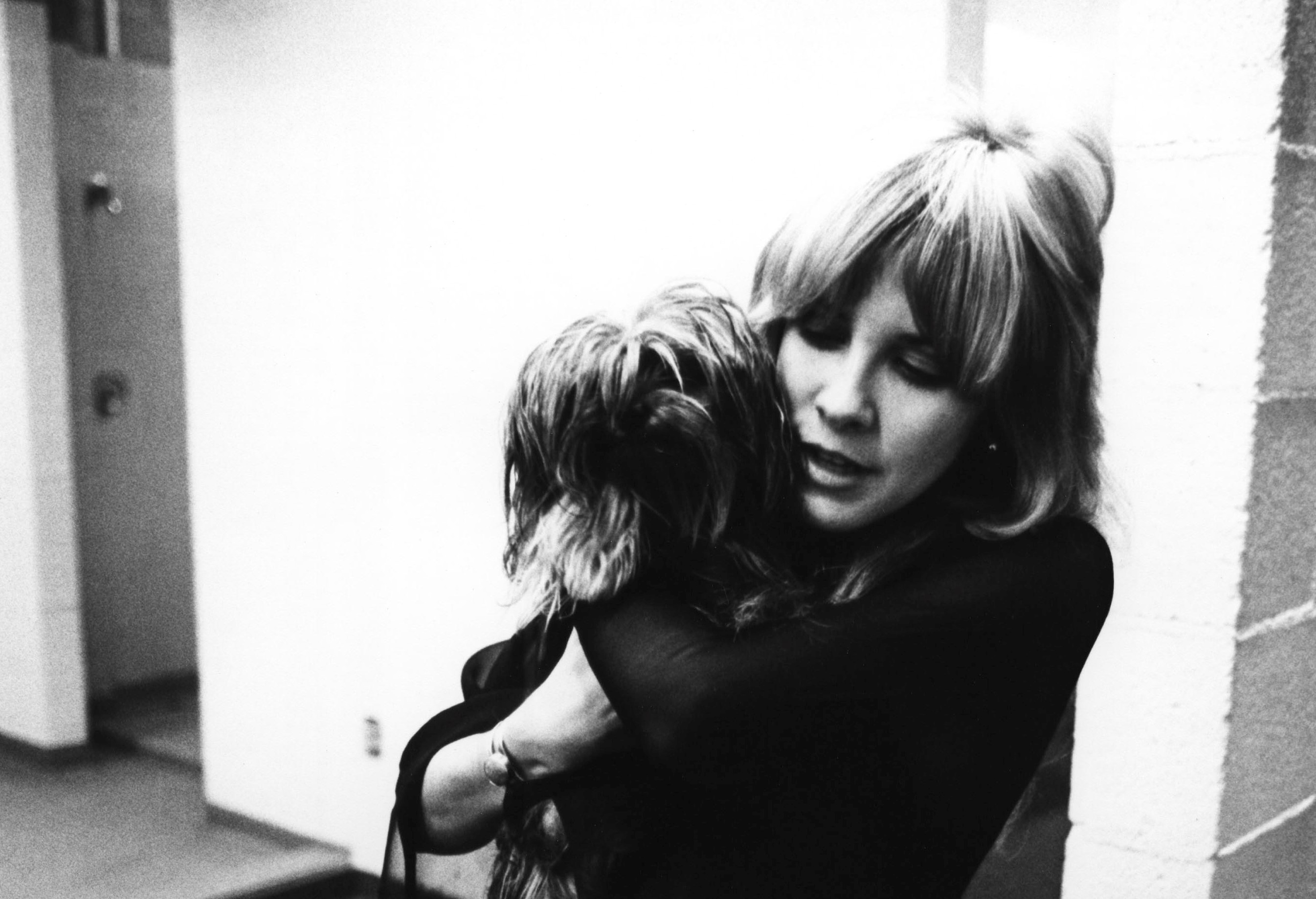Stevie Nicks in a black top holding a dog.