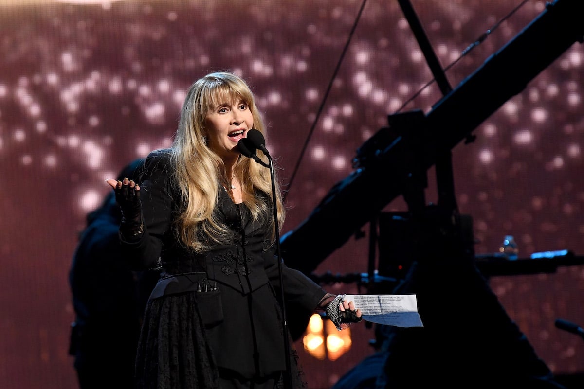 Stevie Nicks speaks into a microphone on stage.