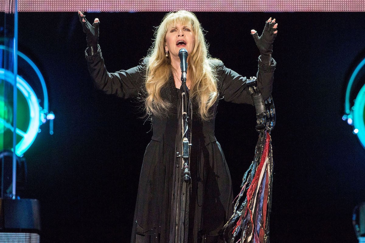 Stevie Nicks performs on stage with a tambourine.