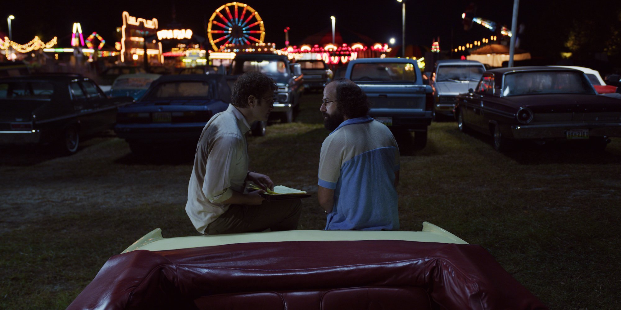 Alexei and Murray sit on a car at the Fourth of July carnival in Hawkins, Indiana in a production still from 'Stranger Things' season 3. How will the show address what happened in Hawkins in 'Stranger Things' Season 4?