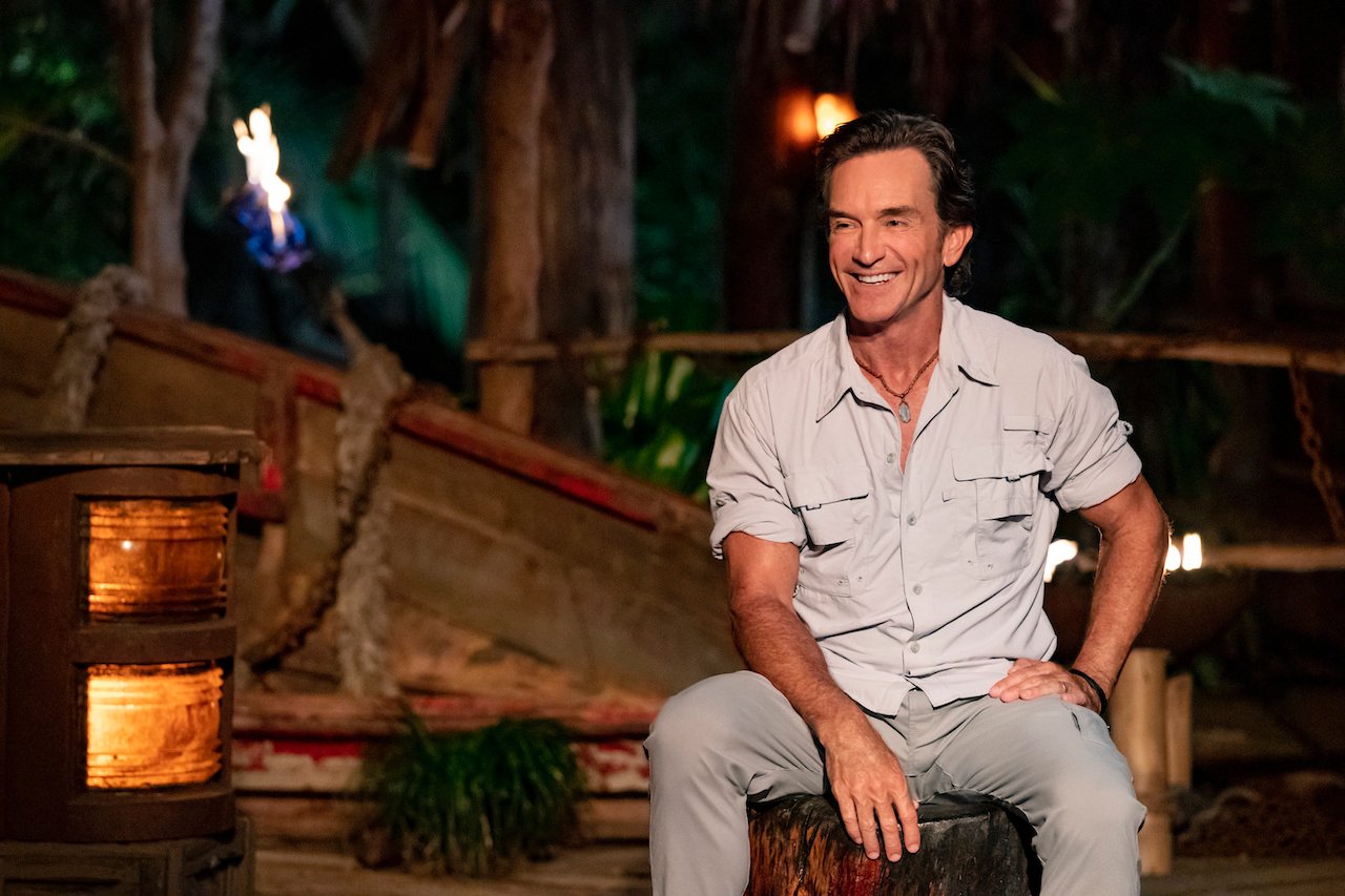 Jeff Probst on 'Survivor' sits at Tribal Council in a button down shirt and pants.