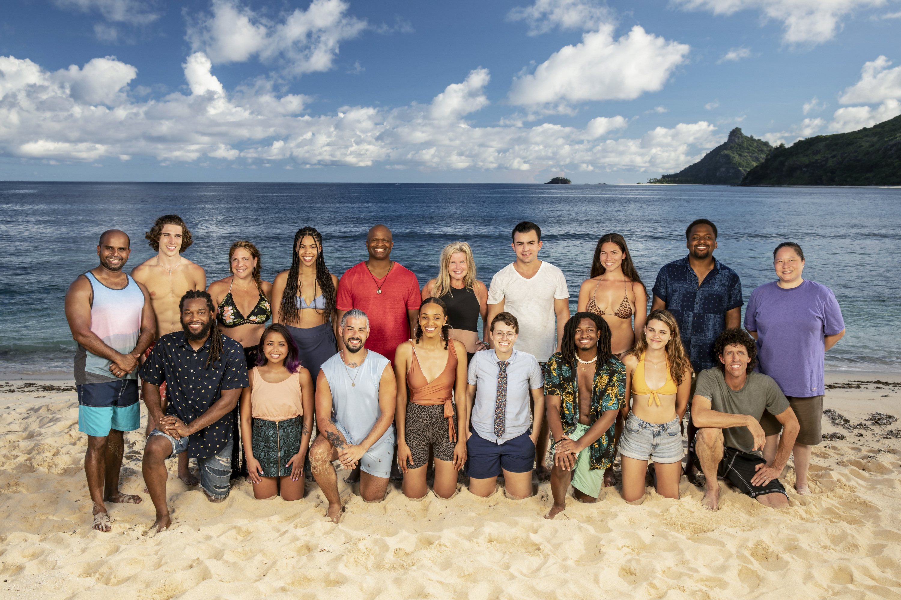 The cast of 'Survivor' Season 41 poses for a group photo on the beach. Ten castaways stand in the back row and the eight other contestants kneel in front of them.