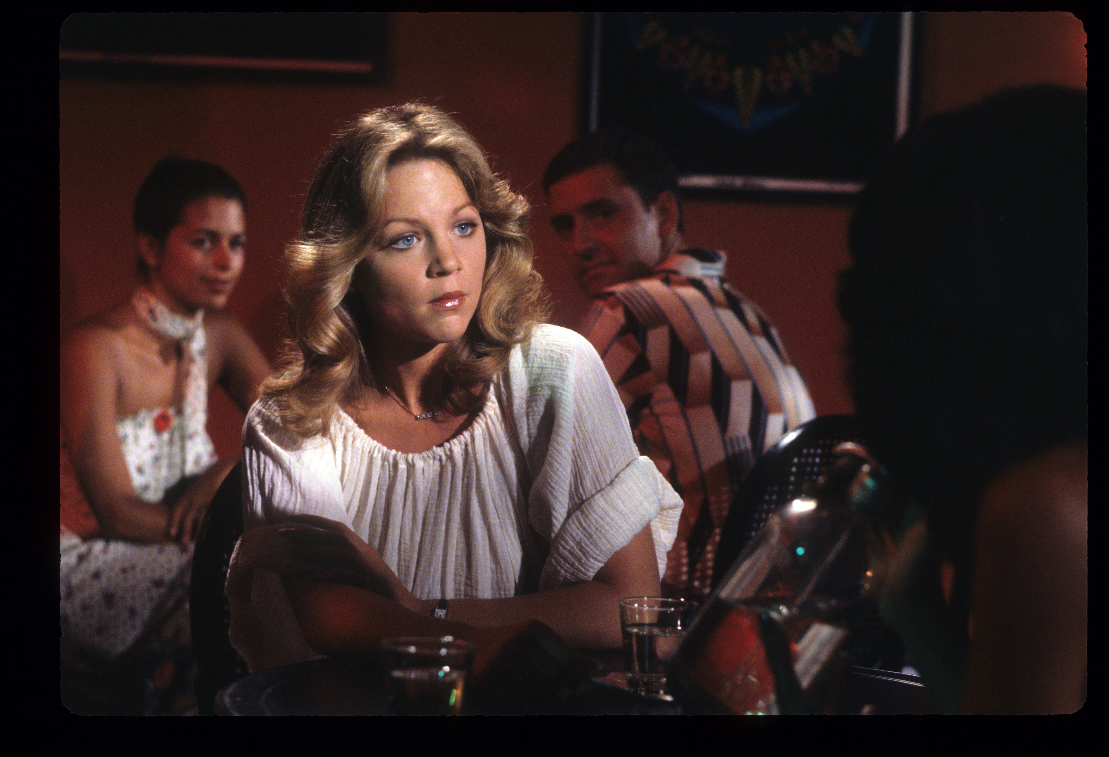 Lisa Hartman, wearing a white blouse and leaning against a bar, in 'Tabitha'