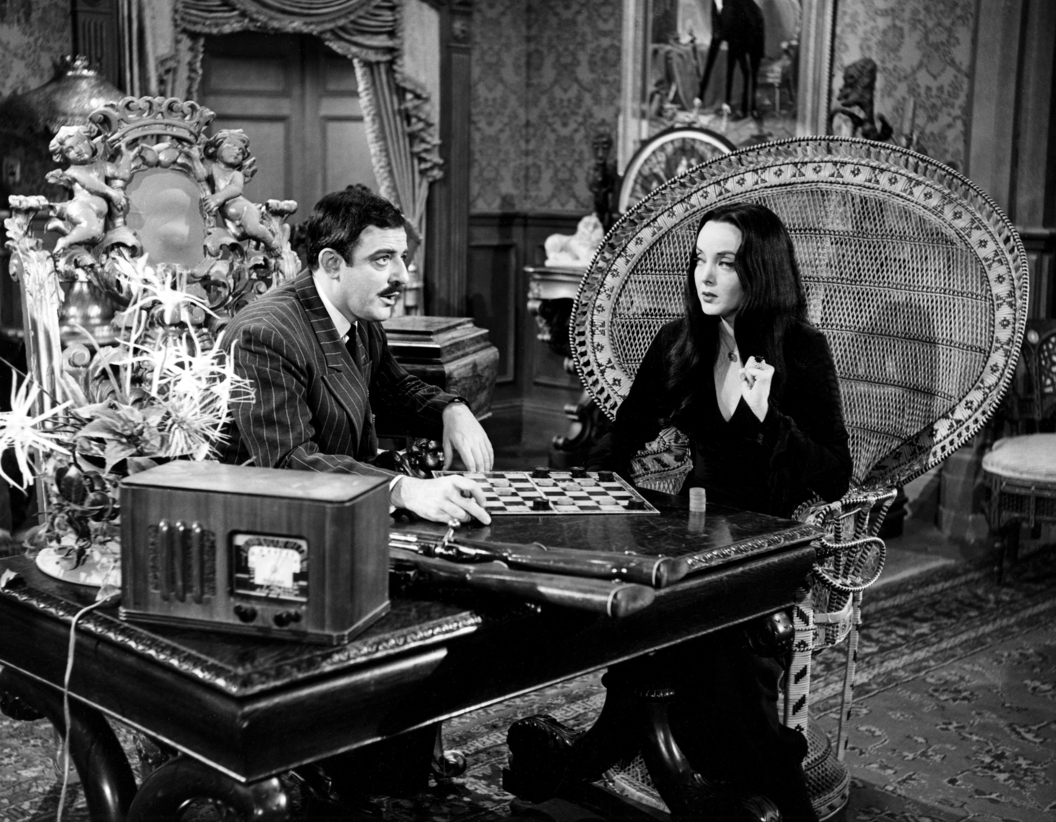 John Astin in a suit and Carolyn Jones in a black dress in a scene from 'The Addams Family.'