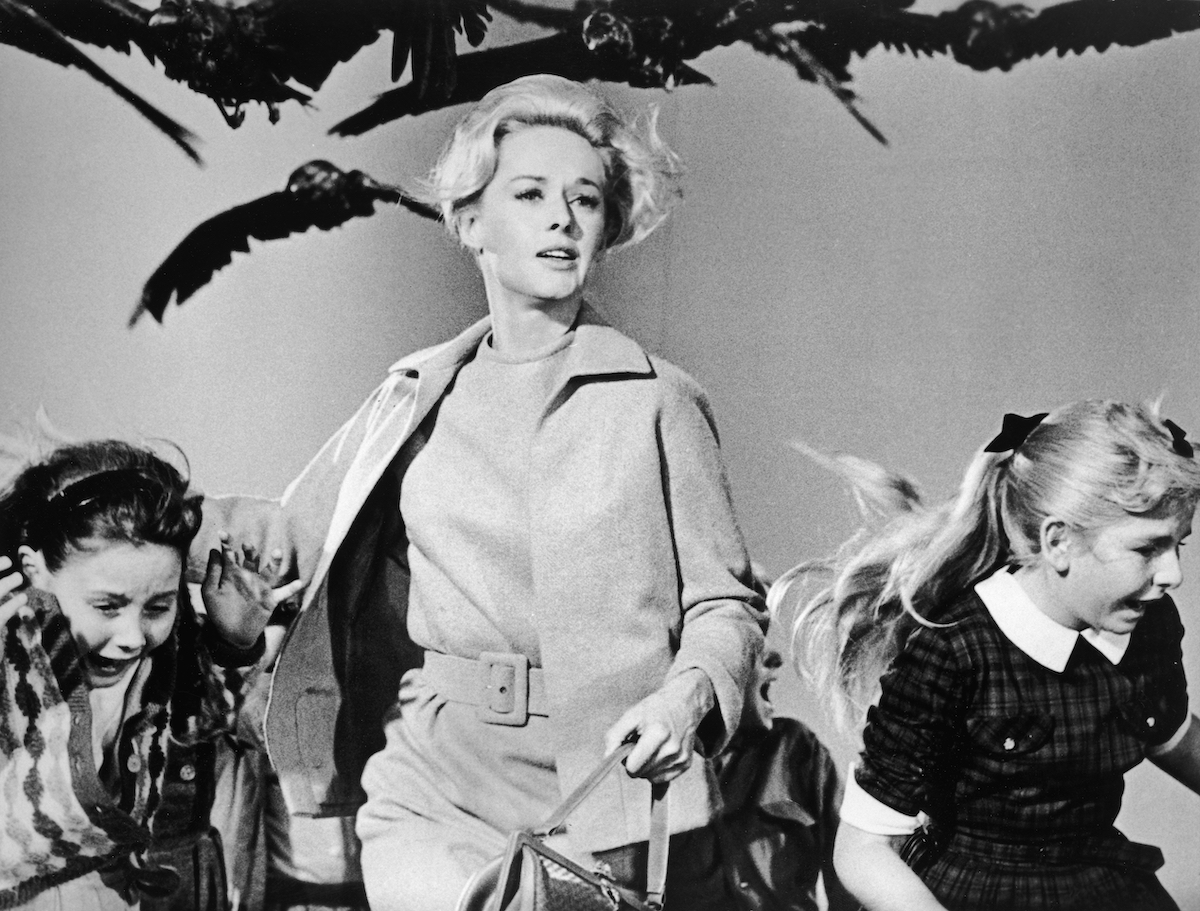 Tippi Hedren and small children running from crows in a scene from 'The Birds'