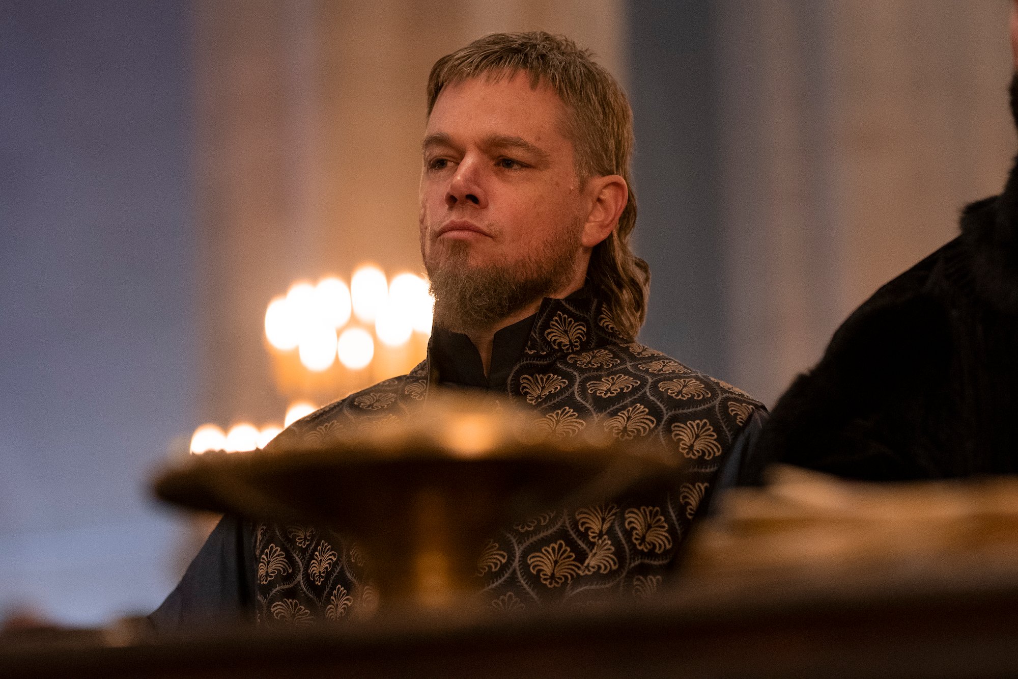 The Last Duel star Matt Damon sits in a candlelit chambe