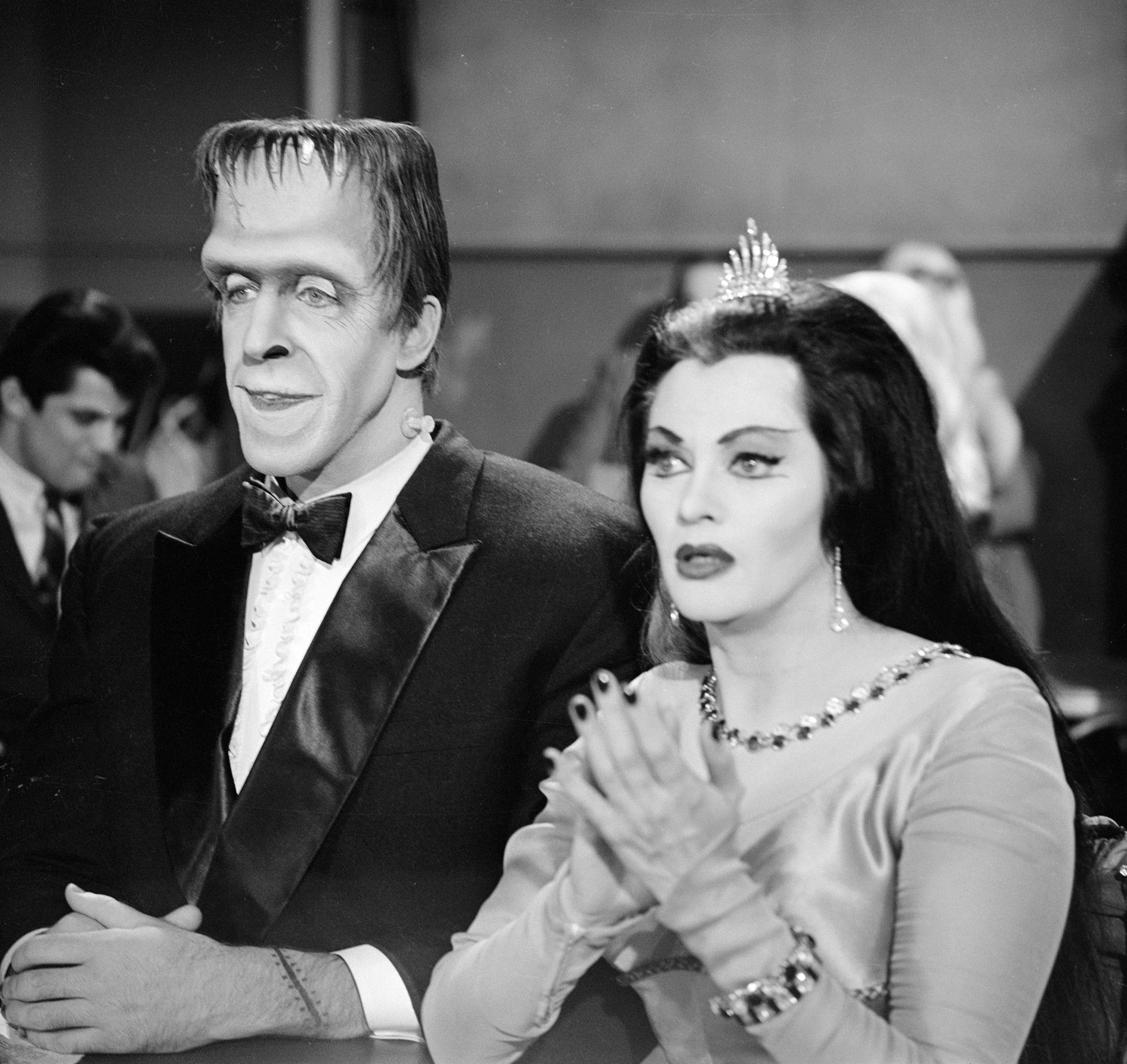 'The Munsters' actor Fred Gwynne in his Frankenstein costume and tuxedo, and Yvonne De Carlo dressed as a vampire in an evening gown for a scene in the CBS comedy.