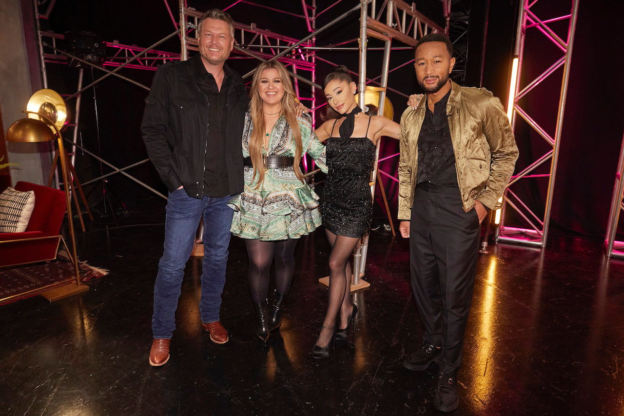 Blake Shelton, Kelly Clarkson, Ariana Grande, John Legend on 'The Voice' have their arms around each other as they stand next to each other.