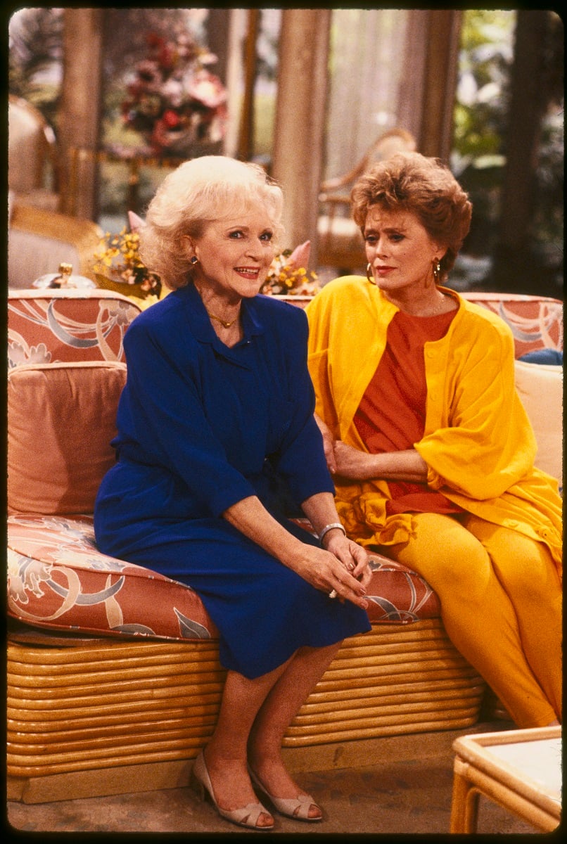Rose Nylund and Blanche Devereaux sit o the couch in 'The Golden Girls'