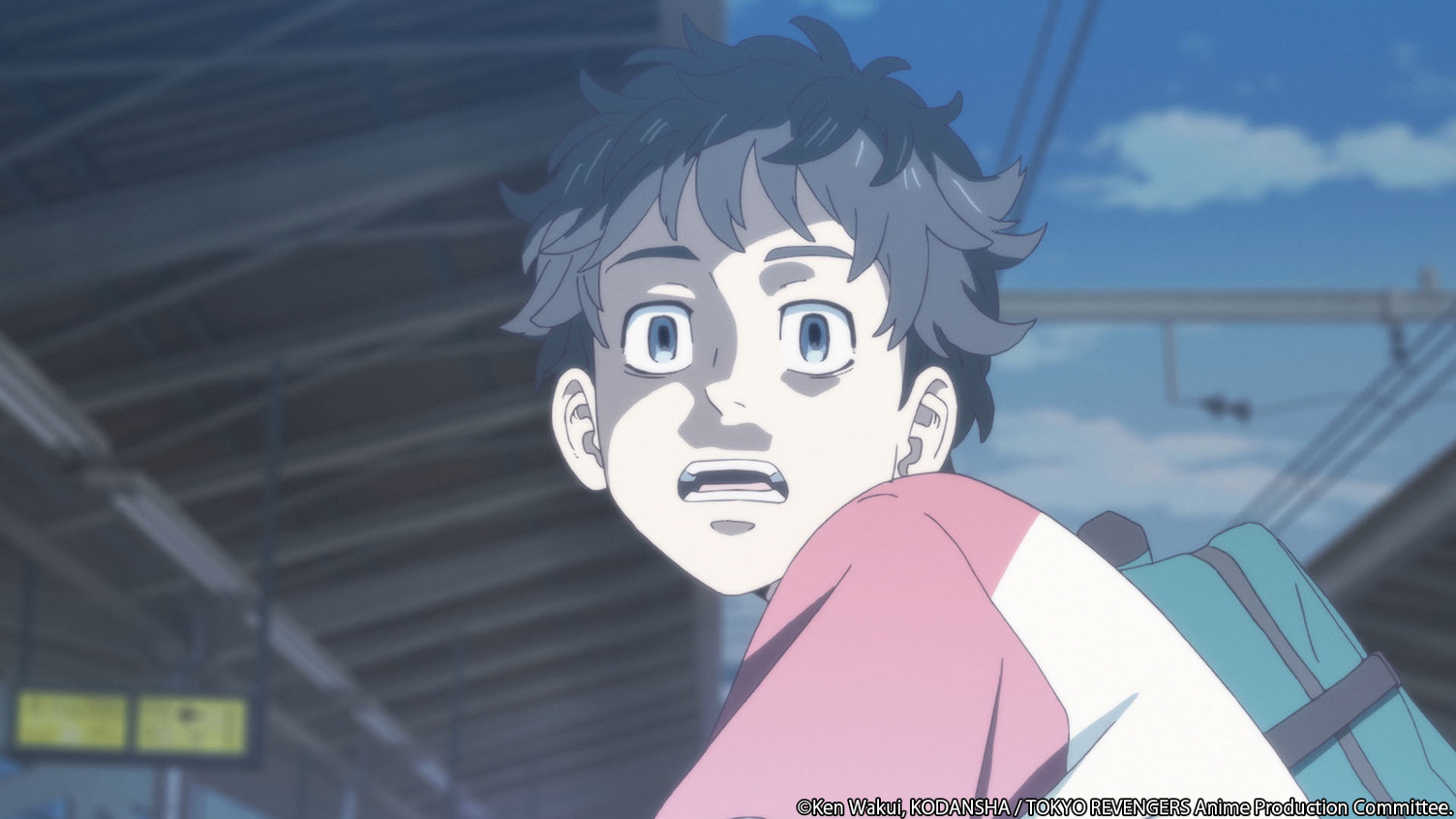 An image from 'Tokyo Revengers' Episode 1, which was adapted for live-action. It shows Takemichi about to get hit by a train. He looks shocked and scared, and the headlights are shining on him.