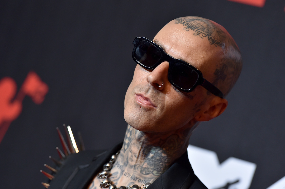 Travis Barker in front of a black background wearing sunglasses
