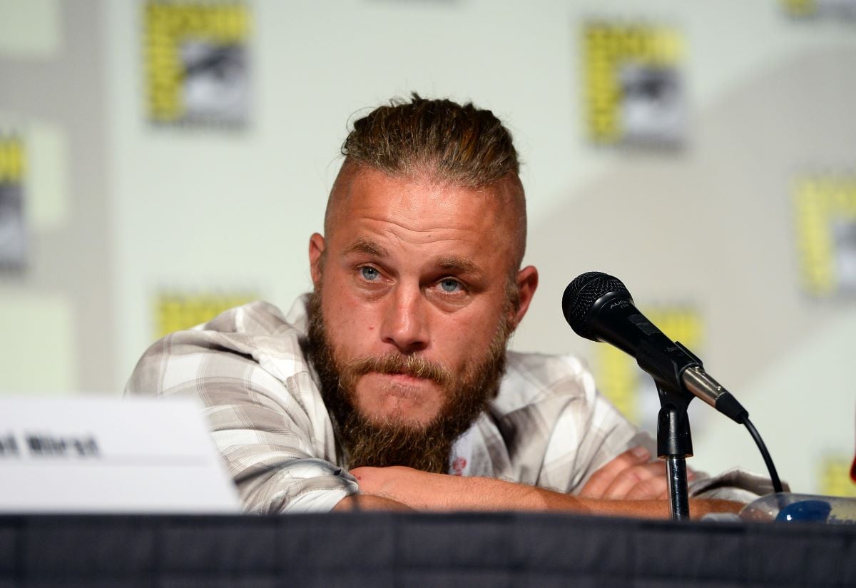 Travis Fimmel leans on a table in front of a mic