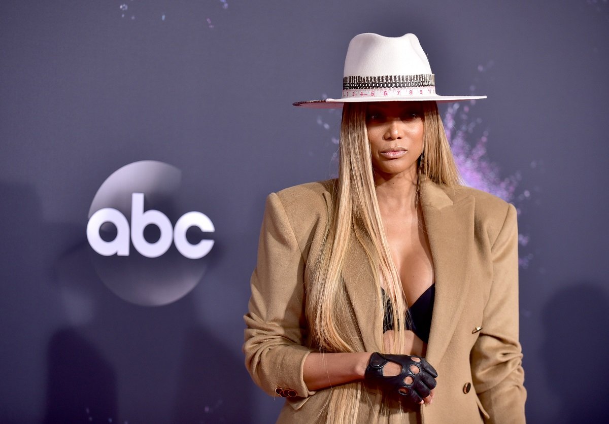 Tyra Banks posing in a brown suit