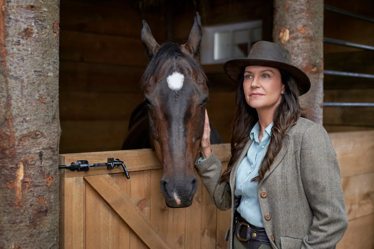 Wendy Crewson (Tess) standing next to a horse in a stable in 'When Hope Calls' Season 1