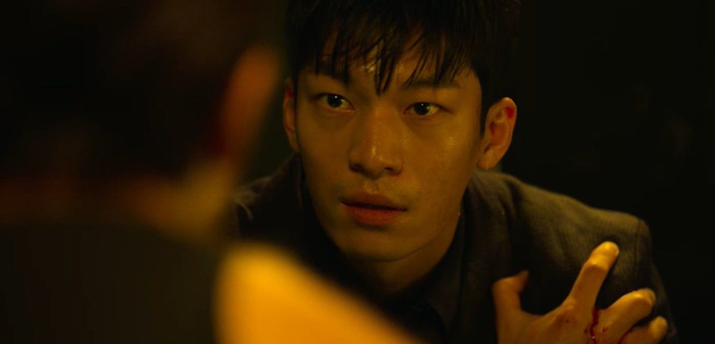 Wi Ha-joon as Hwang Jun-ho in 'Squid Game' K-drama holding his shoulder facing actor Lee Byung-hun.