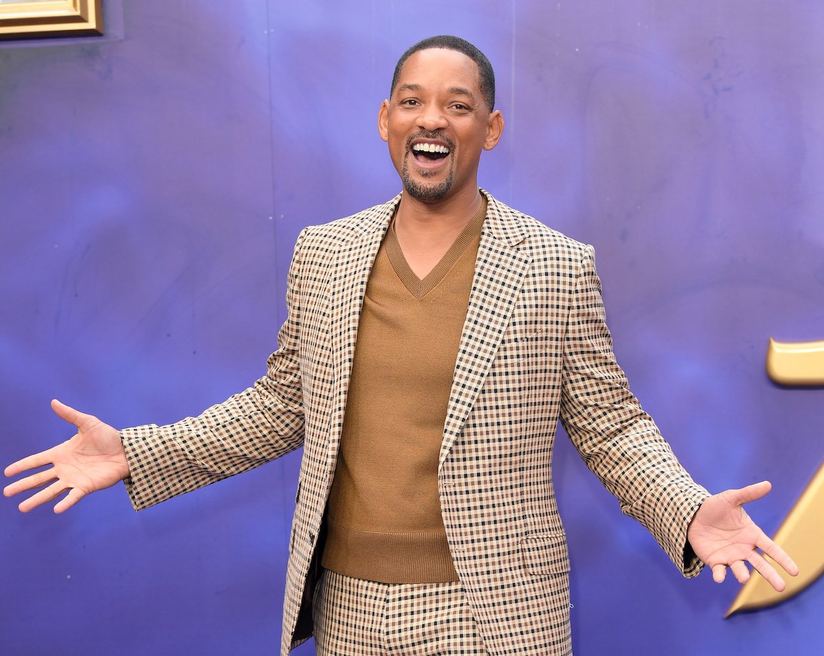 Will Smith spreads his arms and smiles for the camera at an event.