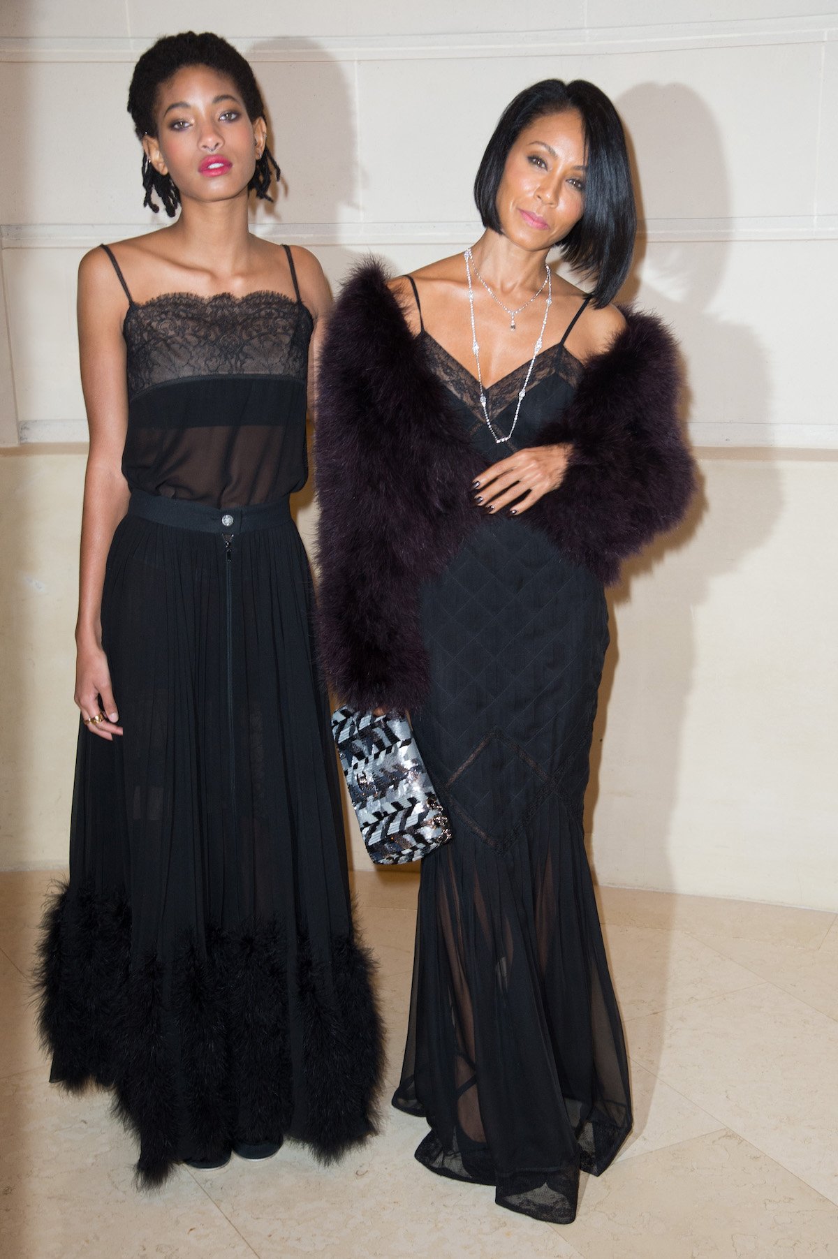Willow Smith and her mother Jada Pinkett Smith pose together in matching black dresses at a event.