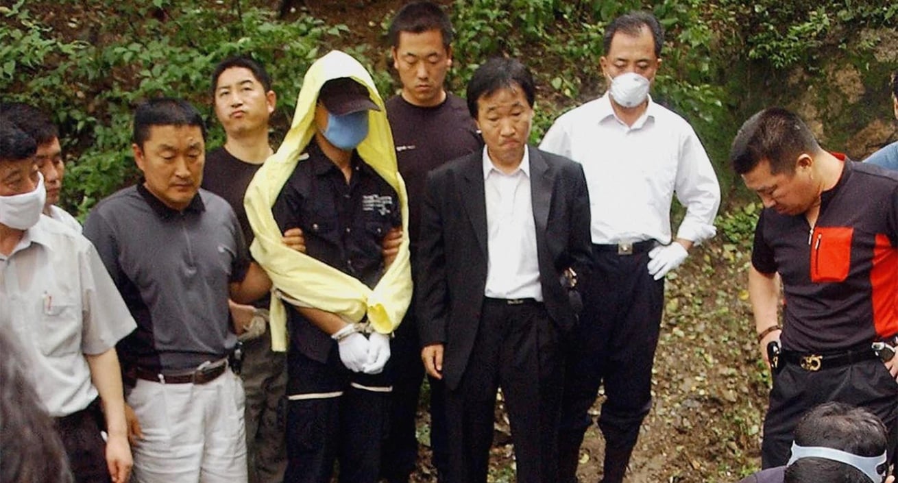 Yoo Young-chul at crime scene in 'The Raincoat Killer: Chasing a Predator in Korea' on Netflix held by police