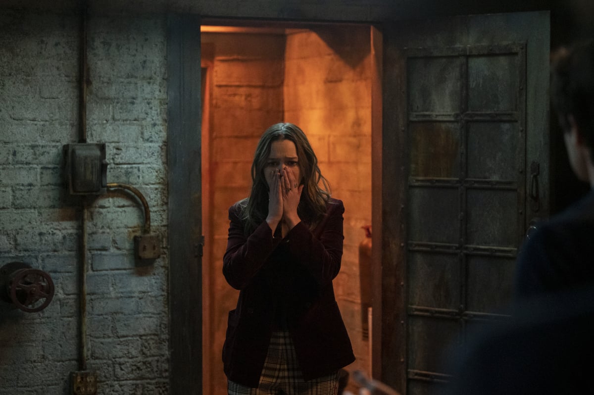 Love Quinn puts her hands over her mouth in surprise in 'You' Season 3. She appears to be in some kind of basement.